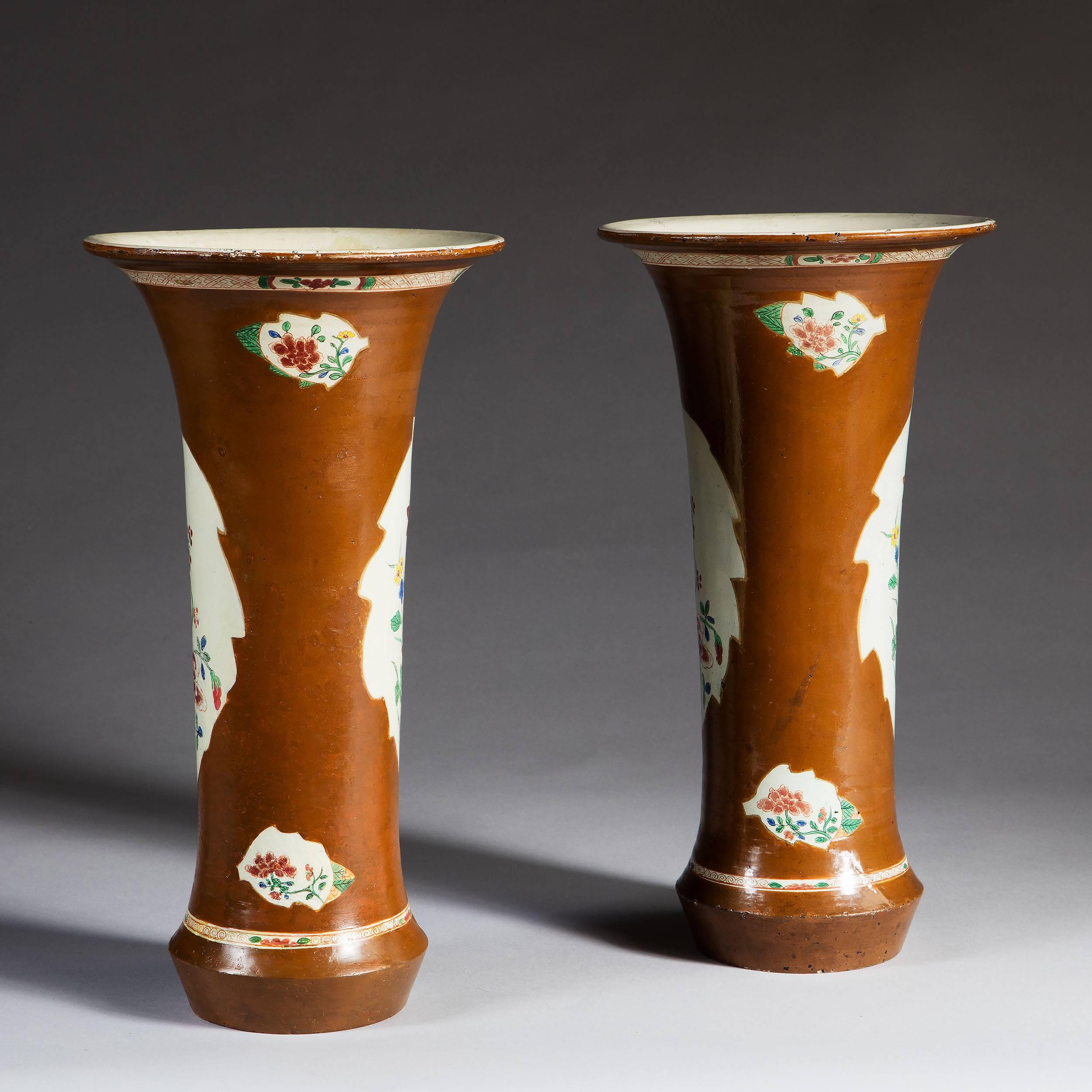 These trumpet vases are European and were made to copy Chinese porcelain vases being exported to Europe from China. 

This pattern is known as Batavia and is characteristic with the five-color panels within a brown lustrous glazed border.