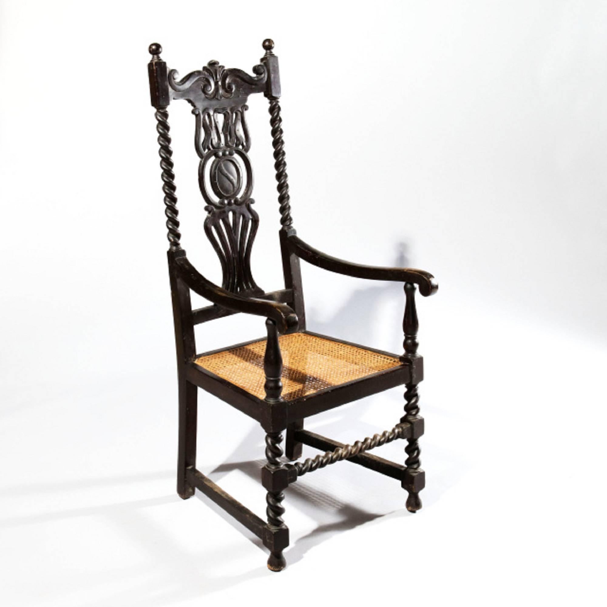 An unusual high back chair, the ebonised wooden frame with spiral supports and unusual pierced splat, the swept arms above baluster supports, cane seats and barely twist legs and front stretcher.