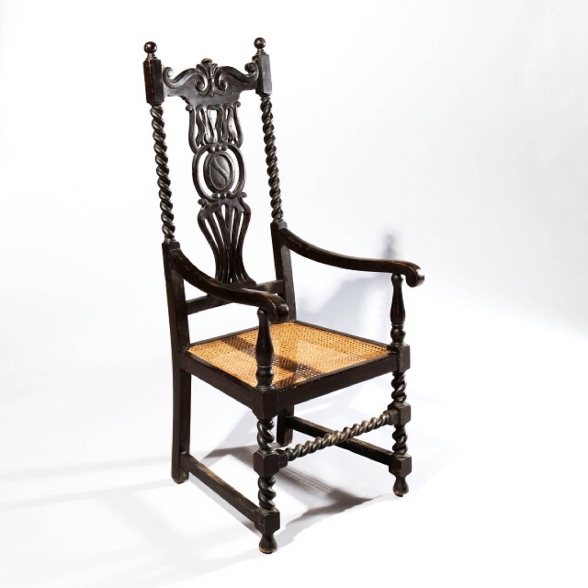 Silla de inusual respaldo alto, armazón de madera ebonizada con soportes en espiral e inusual tablilla perforada, los brazos barridos sobre soportes de balaustre, asientos de caña y patas apenas torcidas y camilla delantera.