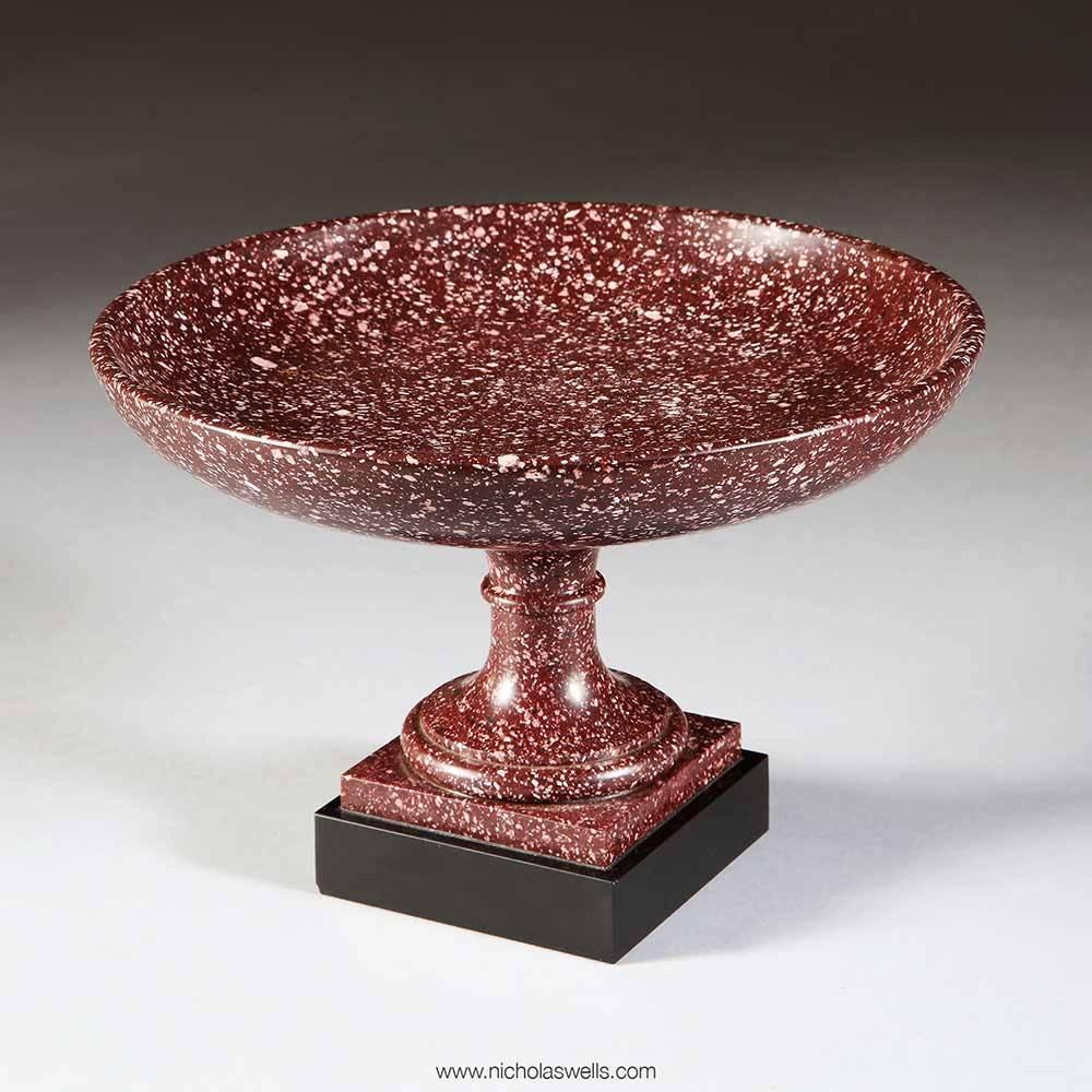 An early 19th century circular porphyry tazza with a turned stem and collar half way up. The whole standing on a black marble plinth.