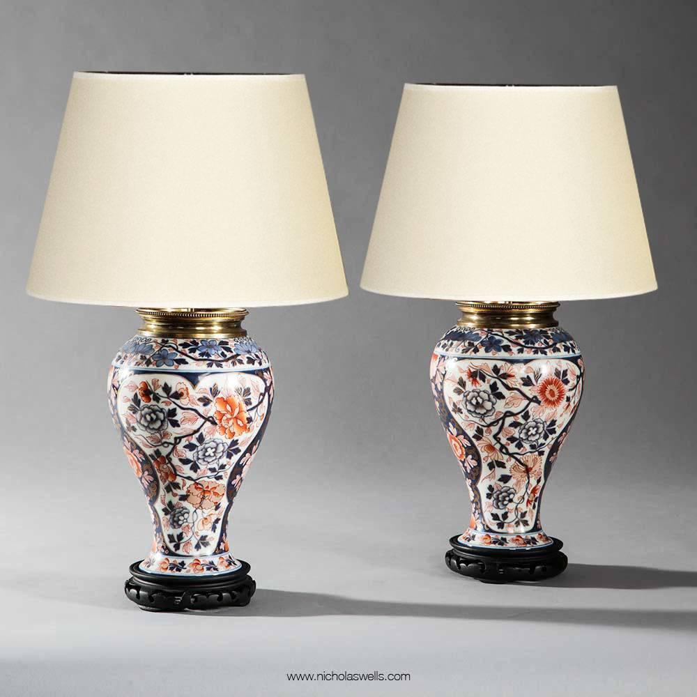 Pair of Imari pattern Bayeux, Veuve Langlois porcelain oil lamps, France. Each of baluster form, decorated with flowers and foliage in polychrome colours of blue, coral and orange on a white ground with gold leaf detailing and fitted with original