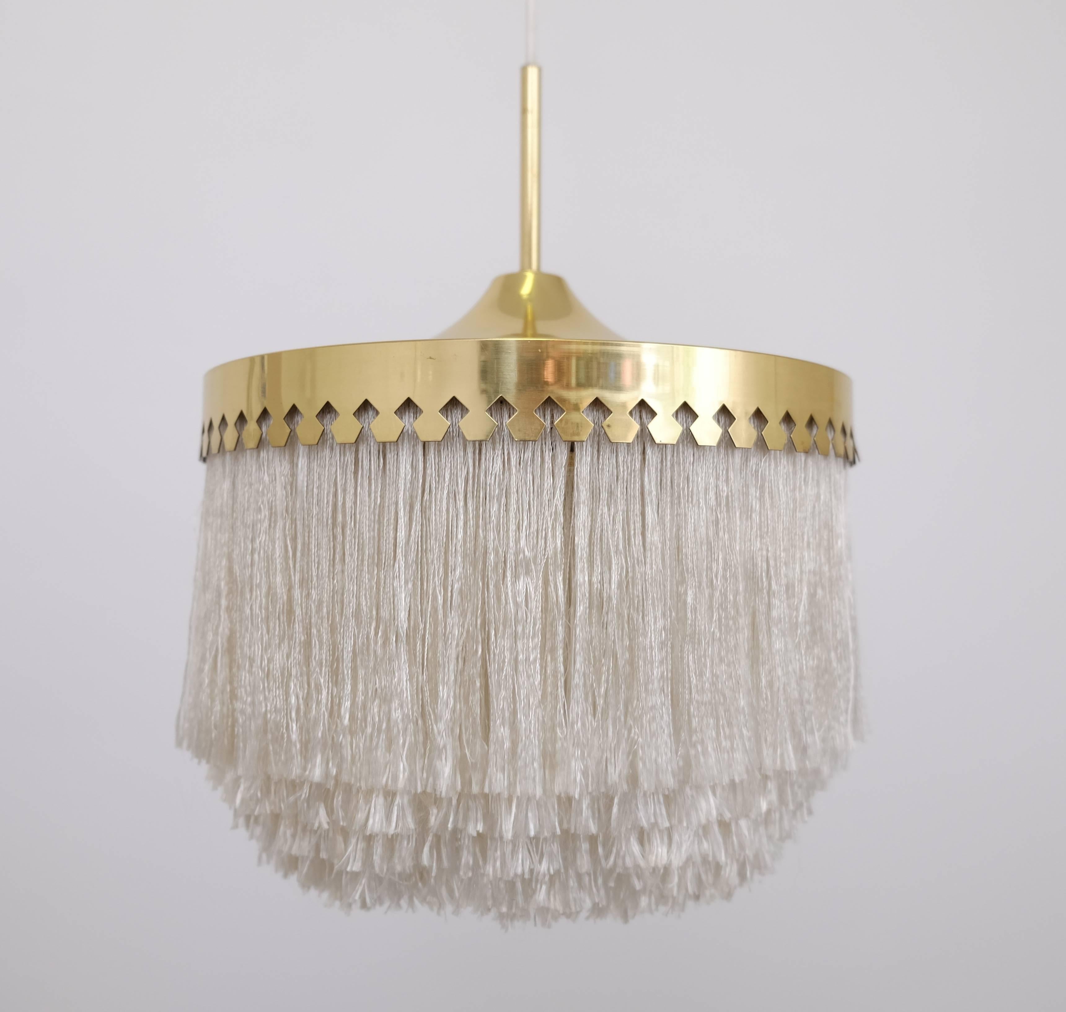 White fringes pendant light with brass frame.
Fitted with one E27 socket. Height of the lamp only from bottom of fringes to top of brass crown approximately 36cm. Diameter 28 cm.
The height is adjustable up to 150 cm.