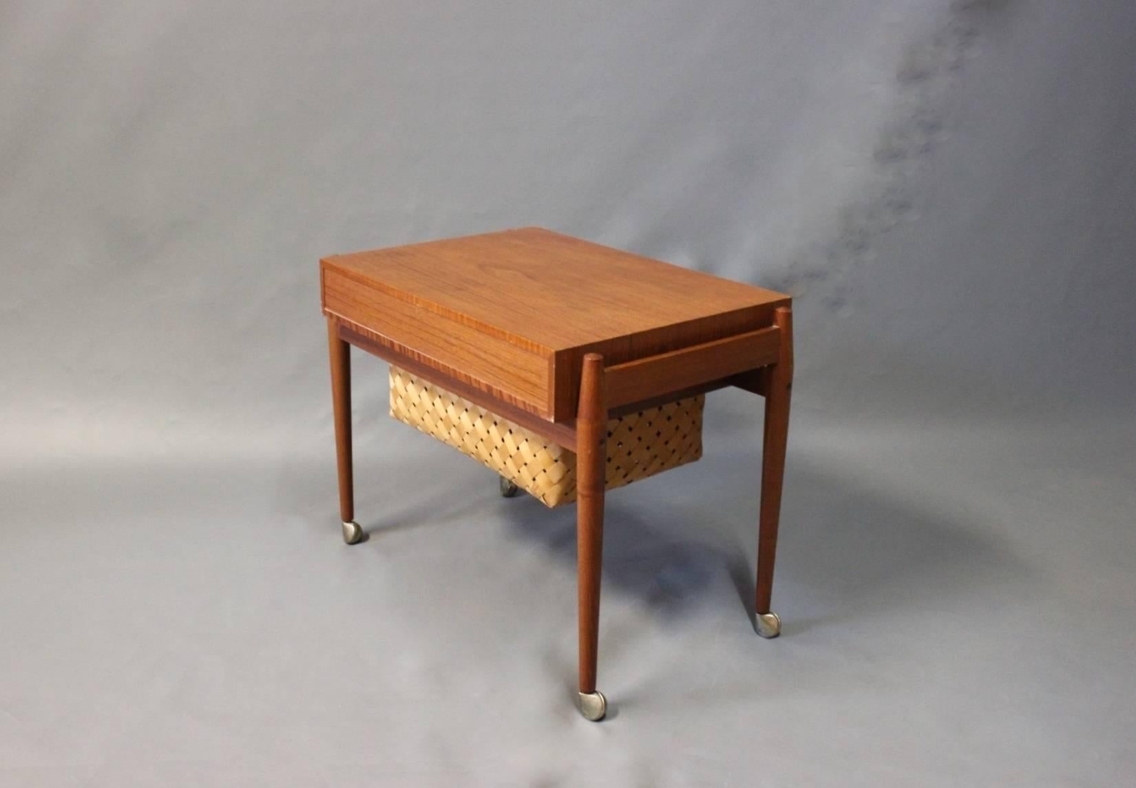 Small sewing/work table in teak and papercord basket and wheels beneath. The table is of Danish Design from the 1960s.