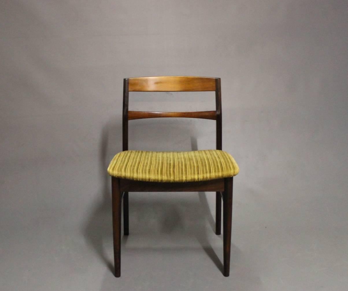 A set of four dining room chairs designed by Arne Vodder and manufactured in rosewood with light fabric from the 1960s is a remarkable representation of mid-century modern design that seamlessly combines organic materials and functional