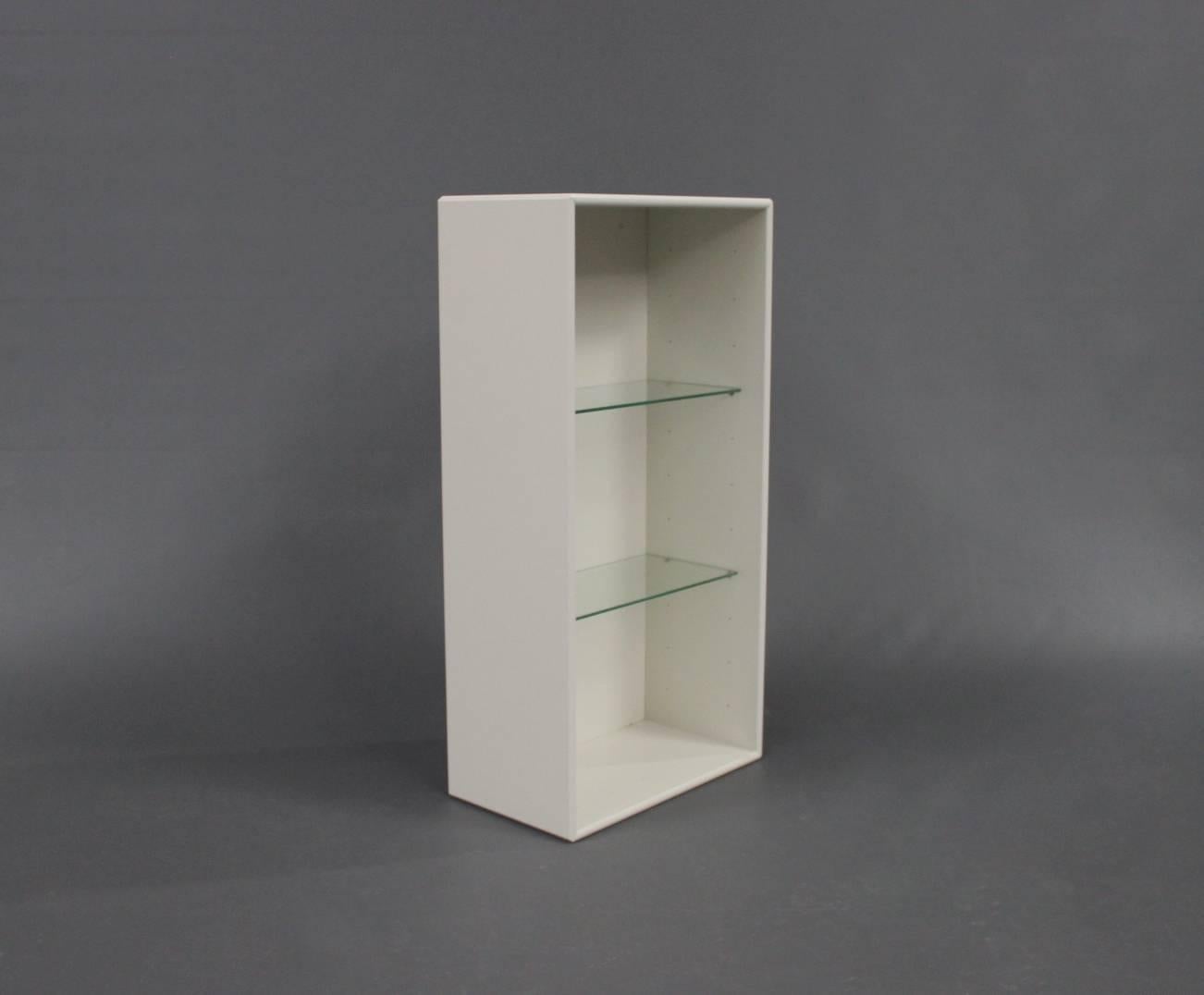 A pair of white bookcases by Montana with glass shelves.