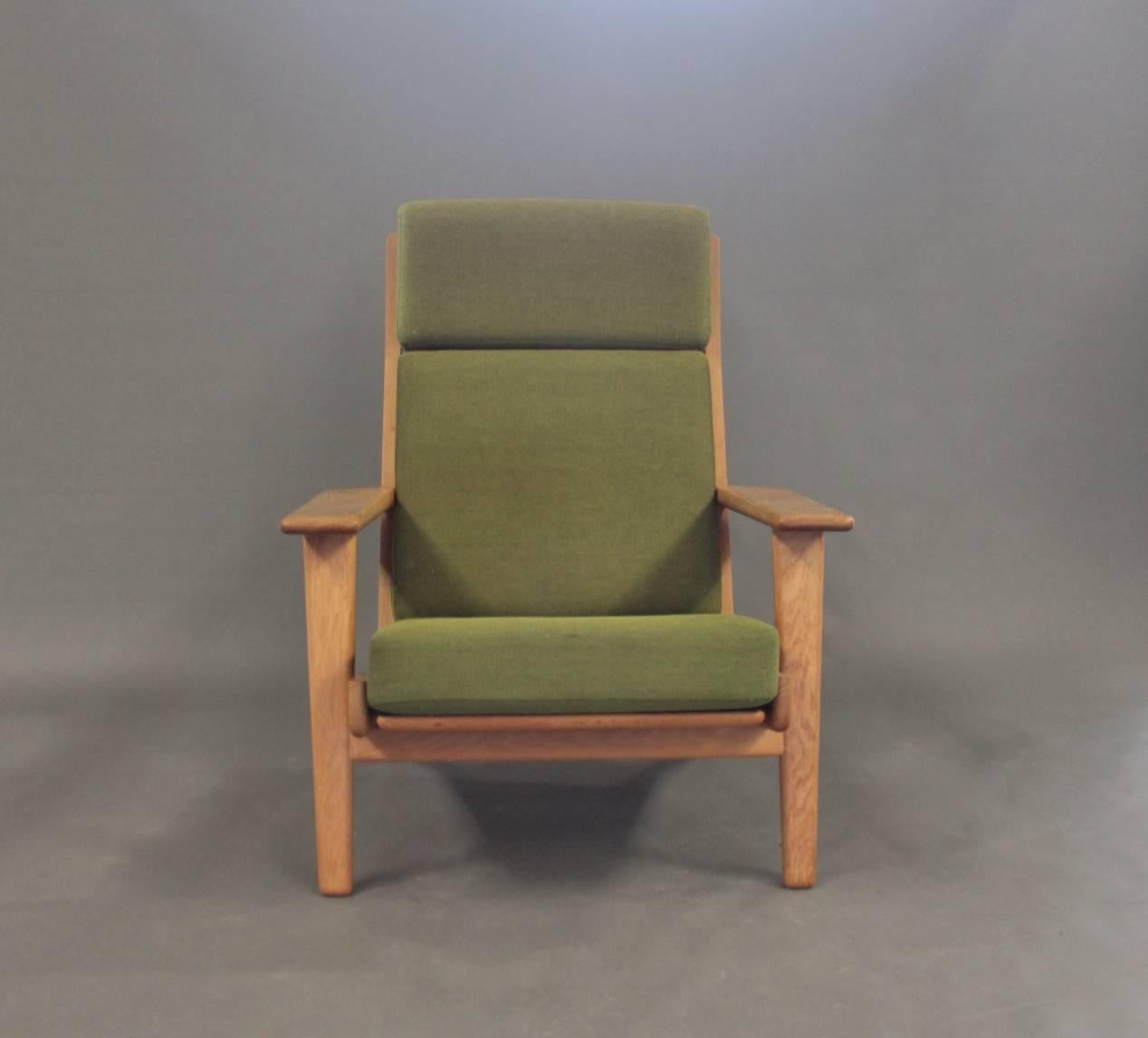 Armchair with high back, model GE290A, designed by Hans J. Wegner in the 1950s and manufactured by GETAMA in the 1960s. The chair is made of oak and the cushions are of dark green upholstery.