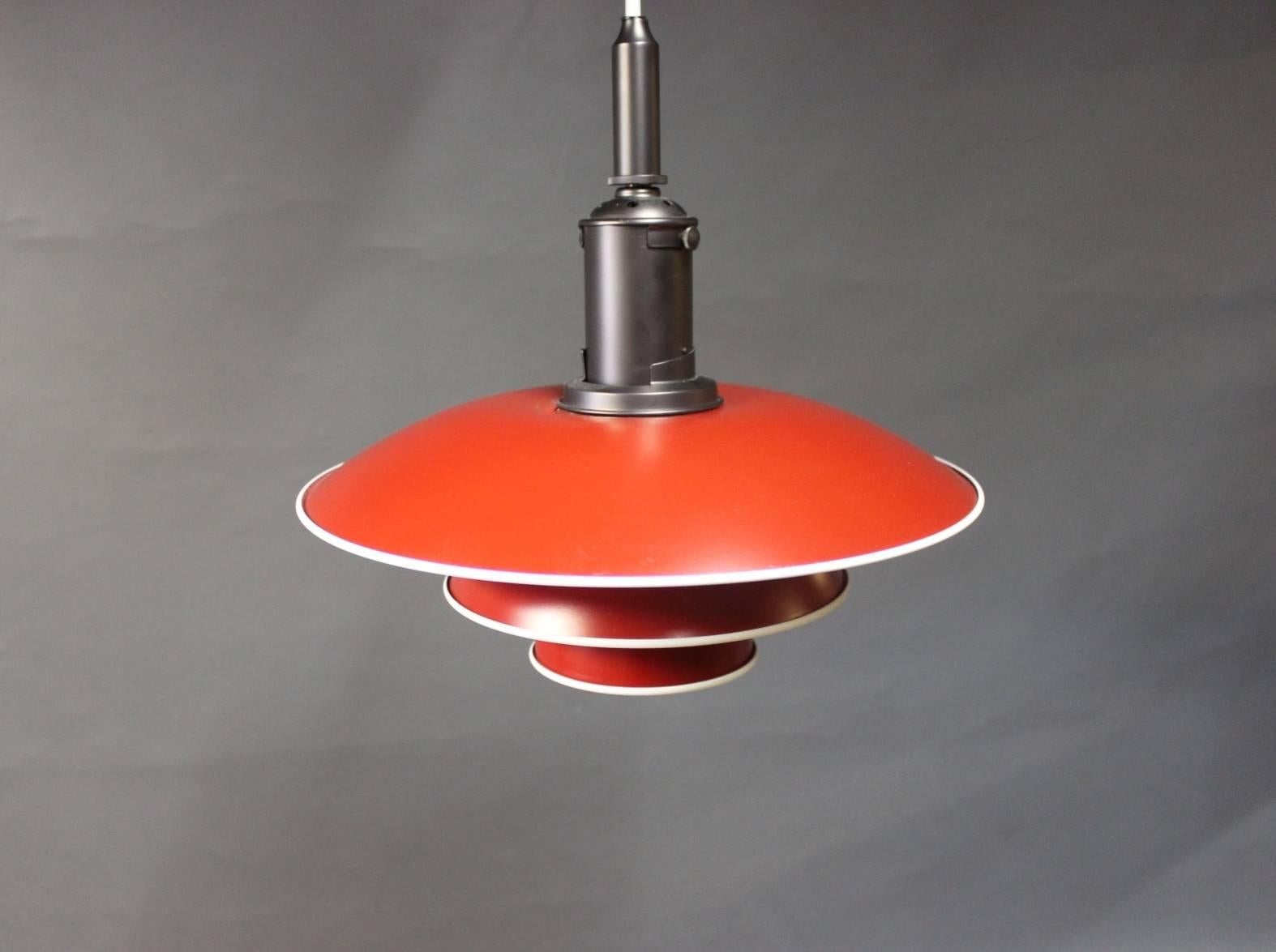 PH3½-3 pendant with red lacquered metal shades with a white edge and mounting in copper. The pendant was launched in occasion of Poul Henningsen's 120th birthday. The pendant is designed from Poul Henningsen's designs from the early 1920s-late 1930s