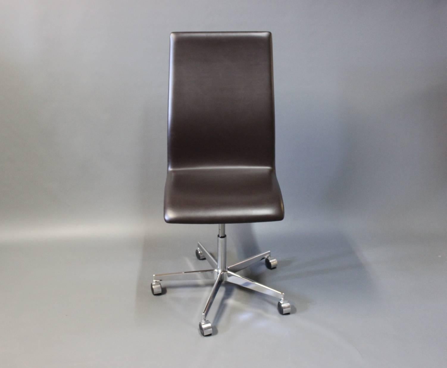 Oxford chair designed by Arne Jacobsen in 1963 and manufactured by Fritz Hansen in 2014. The chair is upholstered in dark brown leather and with wheels beneath. It was originally designed in 1963 only for the professors of St. Catherine's College in