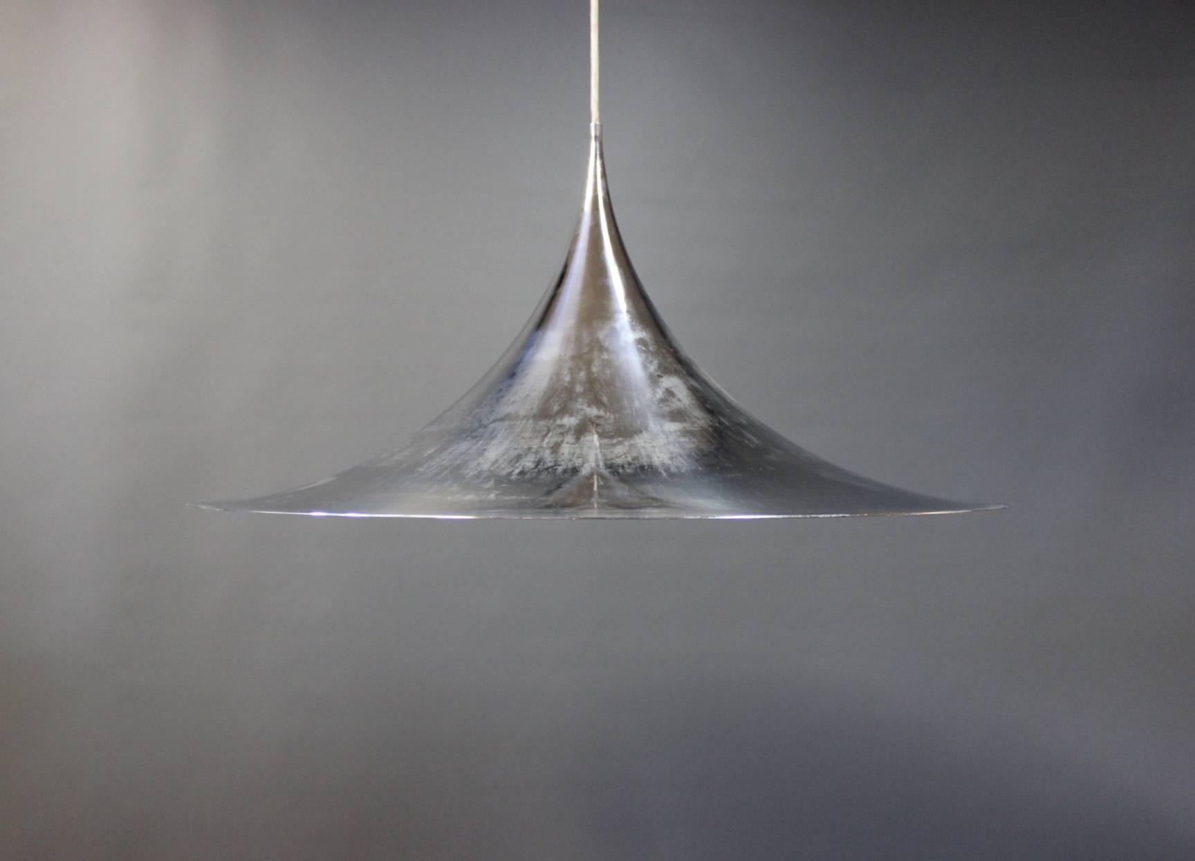 Large Gubi Semi pendant designed by Claus Bonderup and Torsten Thorup in 1955. The pendant is in the color chrome, made of the aluminum and appear patinated. This particular pendant is from the 1960s.