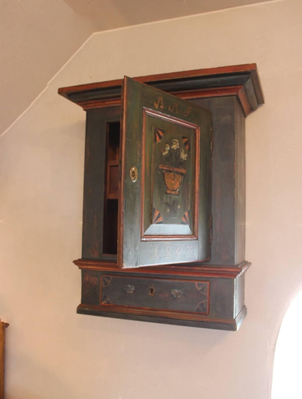A small antique cabinet in painted pinewood. The cabinet is from 1843 and with it's original paint.