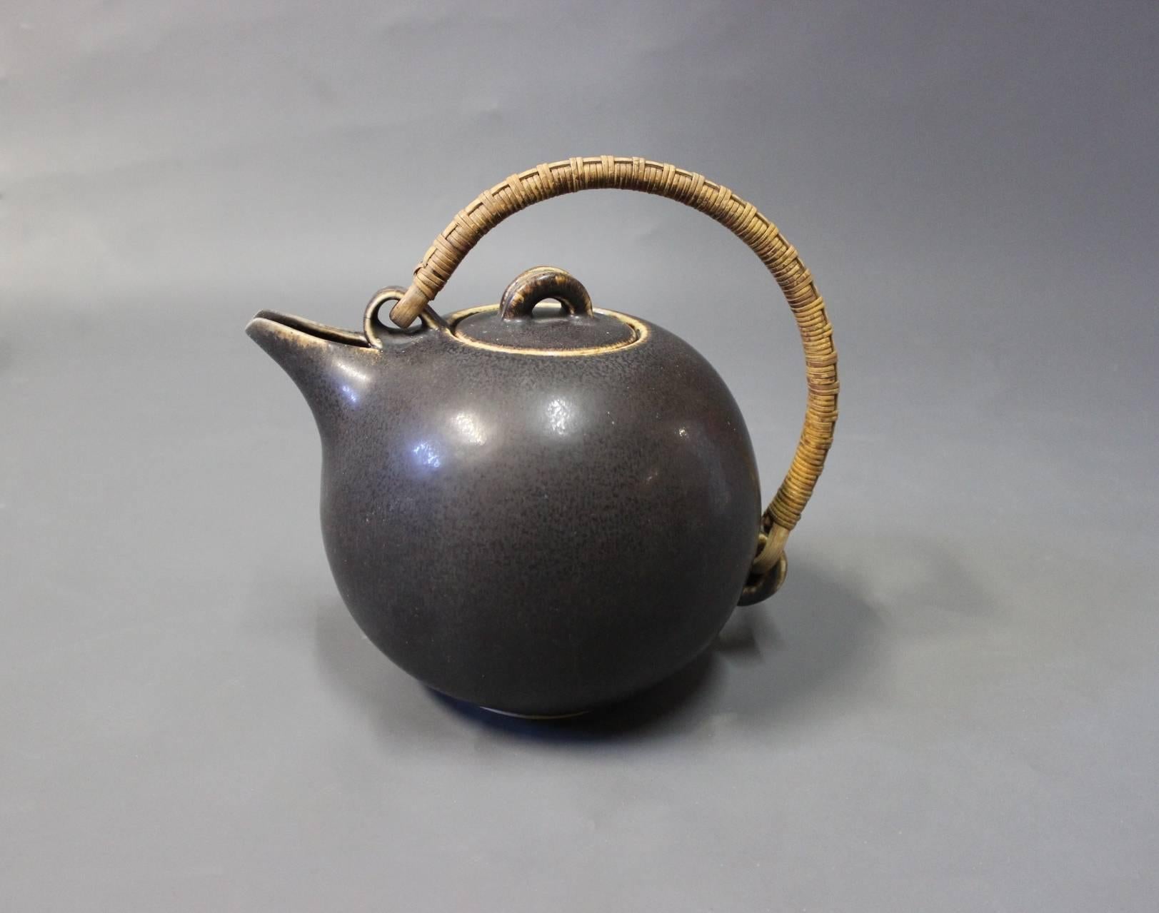 Dark brown glazed stoneware teapot with bast handle from circa 1940s. The teapot is stamped Saxbo Denmark and with the no. 64, designed by Eva Stæhr Nielsen.