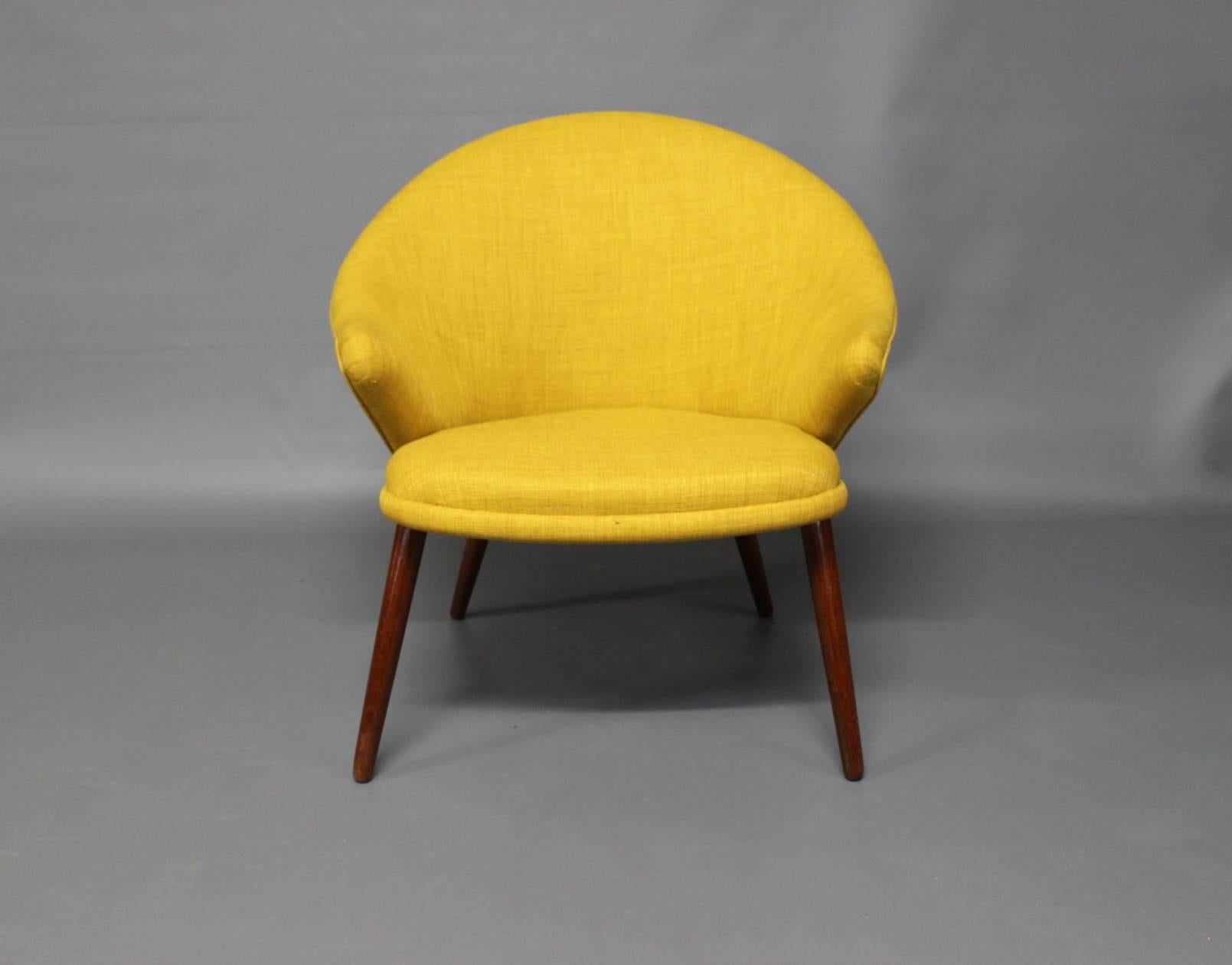Nanna Ditzel armchair upholstered in yellow fabric and legs of teak. The chair was manufactured in Denmark in the 1960s.