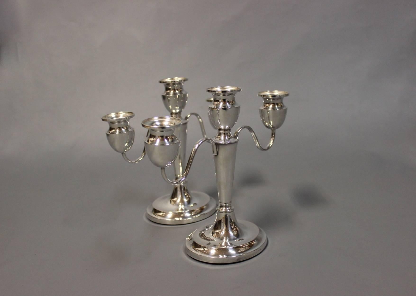 This set of three-armed candlesticks exudes elegance and sophistication, crafted from 830 silver, a hallmark of quality craftsmanship. Each candlestick features a distinctive design, with three gracefully curved arms extending from a central stem,