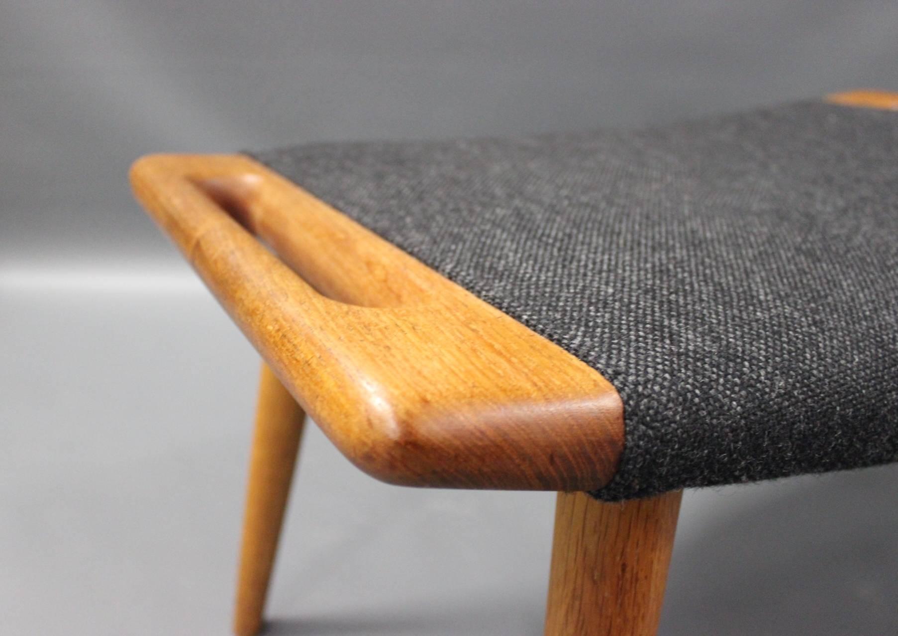 Stool for the papa bear chair, model PP120, designed by Hans J. Wegner in 1954 and manufactured by P.P. furniture. The stool is upholstered in dark grey Hallingdal wool and with legs of teak.