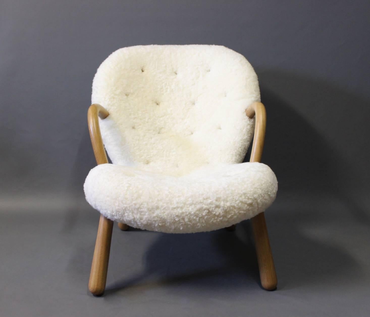 The clam chair originally designed by Phillip Arctander in 1944 and manufactured by Paustian in 2016. The chair is upholstered in sheepskin and with arms and legs of oak.
