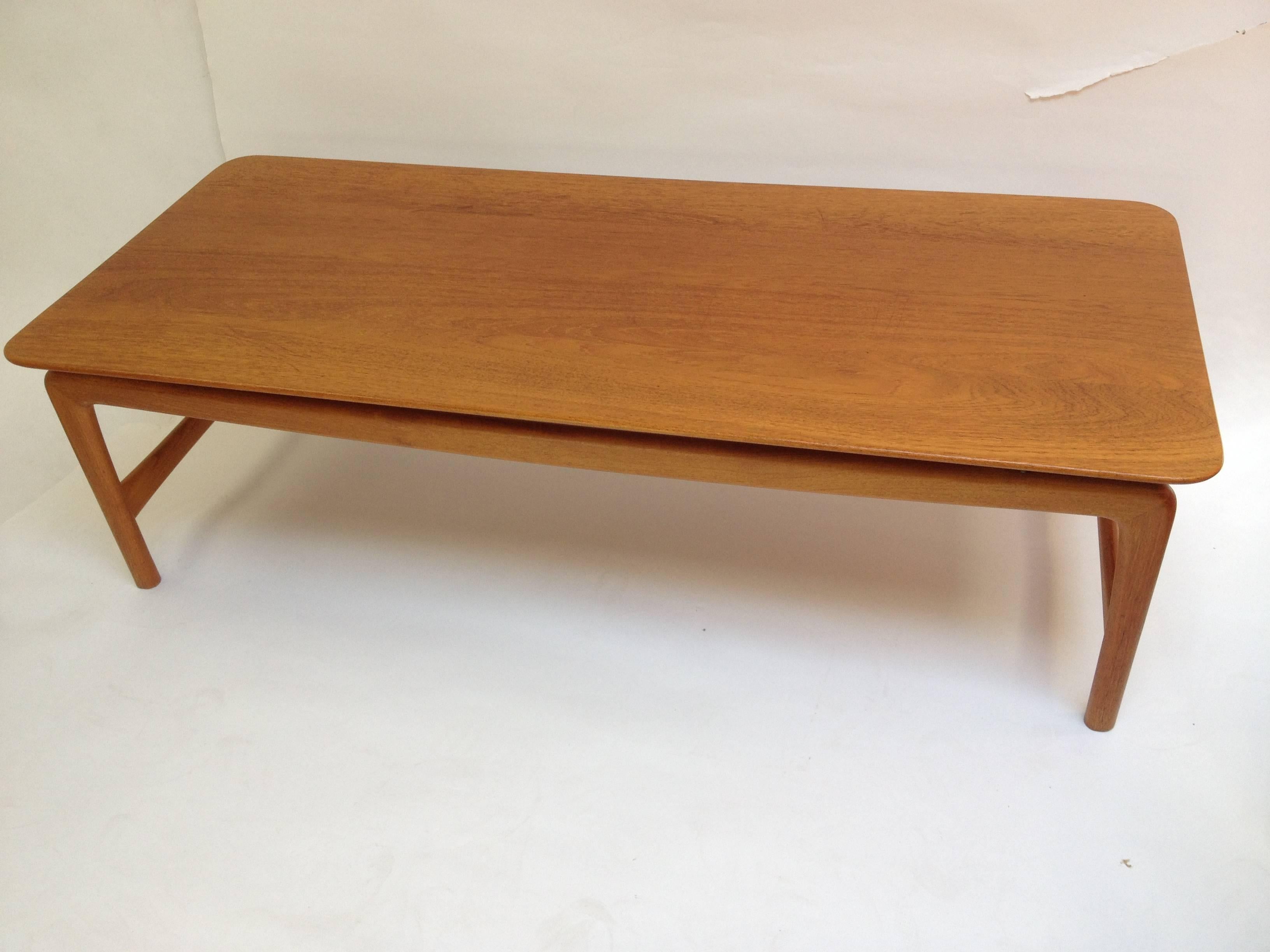 Gorgeous 1950s solid teak coffee table designed by Peter Hvidt for France & Daverkosen. Made in Denmark, this beauty is sleek and classic with lovely brass ball accents. The condition is very good with the original lovely patina, however from use