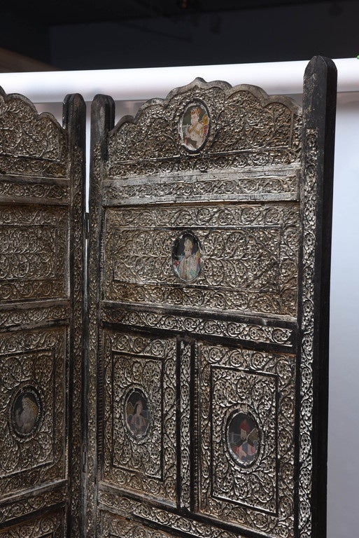 The elaborate hand-carved screen is fashioned from hardwood (possibly padauk) and is appointed with 32 miniature paintings of dignitaries (paintings of possibly Maharajahs and Maharanis). The wood is 