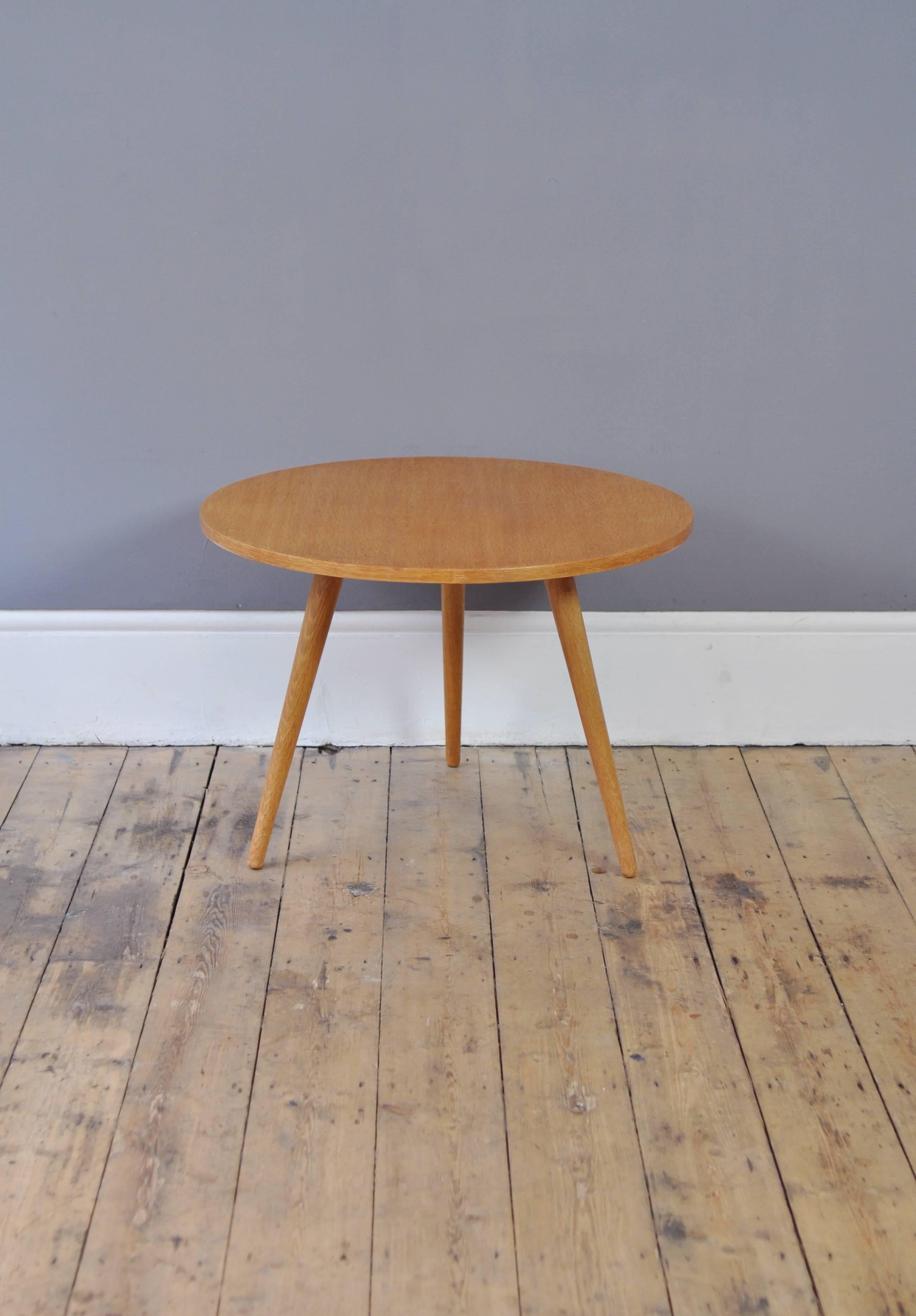 1960s round oak coffee table with standout looks provided by the light toned wood and distinctive tripod legs.