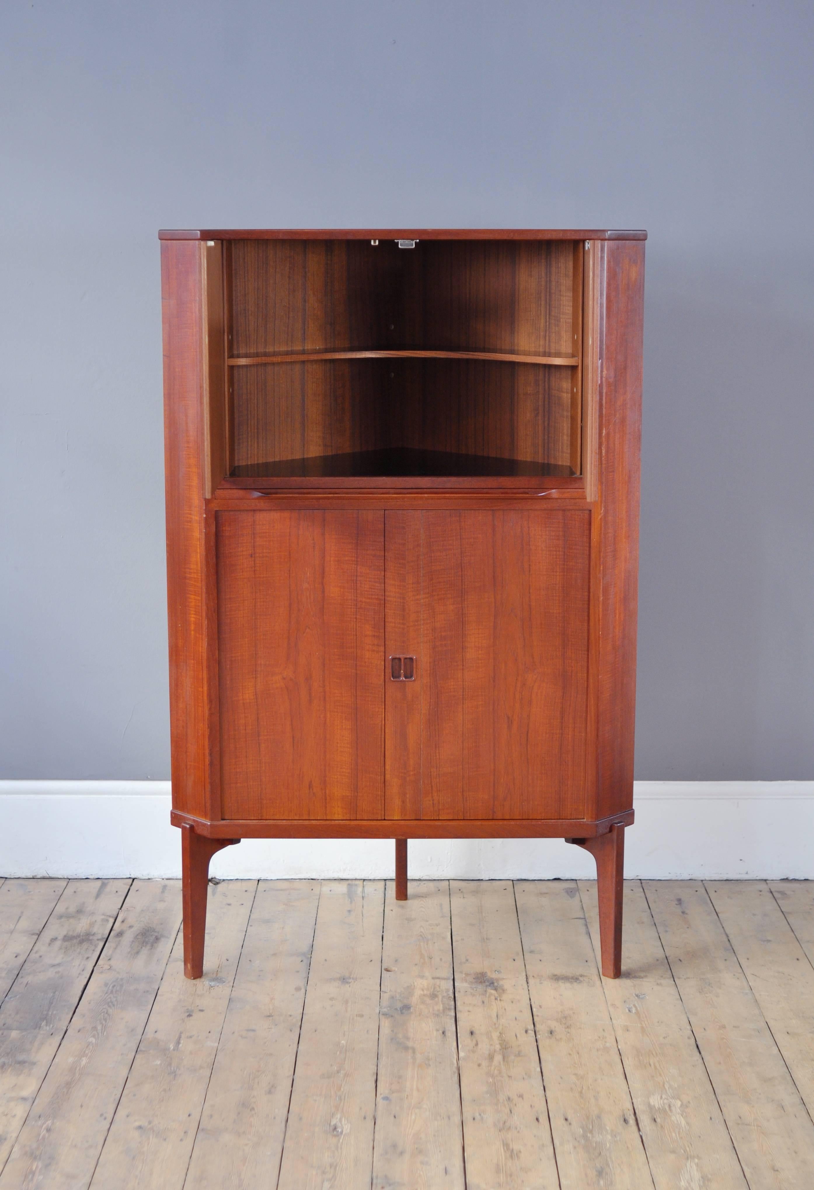 Unusual corner drinks cabinet in teak, with a pull out shelf. Featuring lovely square handles and spacious storage.