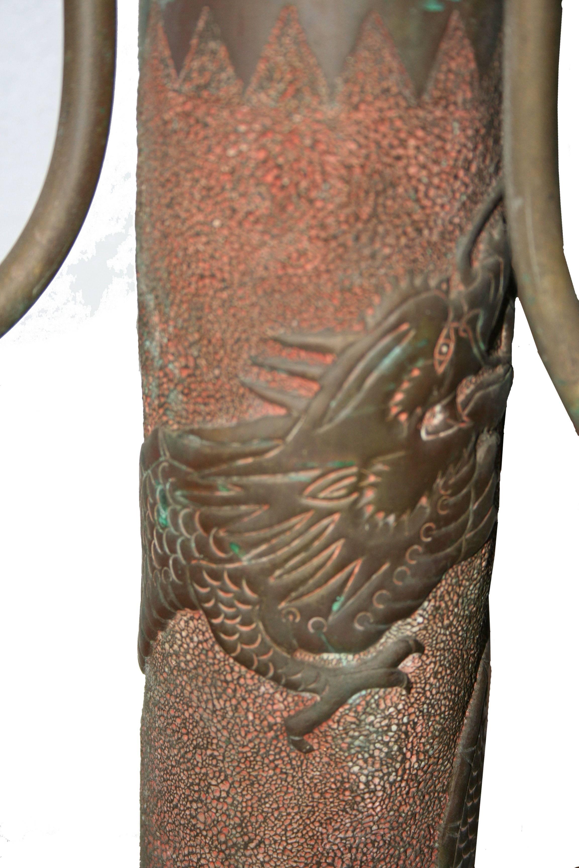 Made from a 3" (76.2MM) WWI artillery shell is this heavily embellished WWI trench art lamp with three arms. Lovely original patina with image of a dragon, done in relief, wrapping around the lamp. The surrounding area is textured, with upper