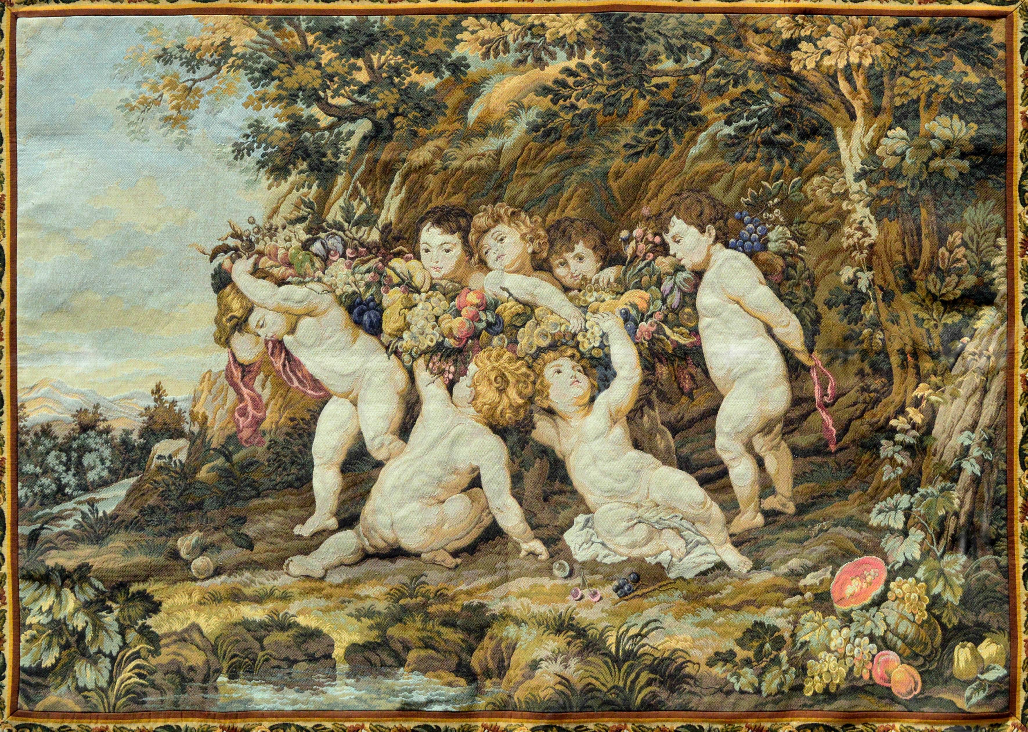 Charming old world Rococo style wall tapestry of cherubs in the style of Boucher by Paris company Panneaux Gobelins. Woven in warm rustic colors with blues, greens, orange, reds and golds depicting harvest party. Could be used as a table topper too.