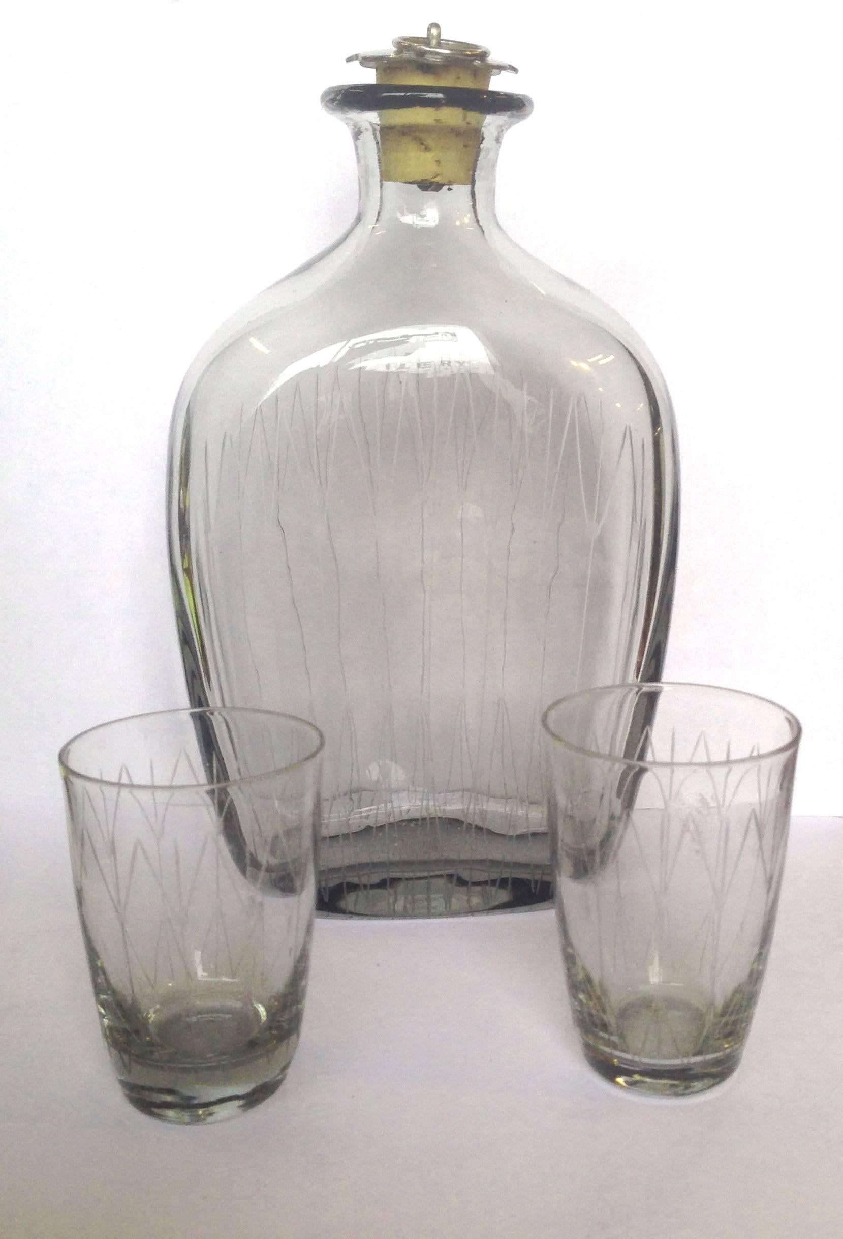 Scandinavian Mid Century Modern Minimalist Schnapps Decanter and Glasses Set 

Delicate and modern vintage etched crystal decanter and two glasses, made in Denmark by Holmegaard Glass Company, circa 1960. The sleek and minimalist design is combined