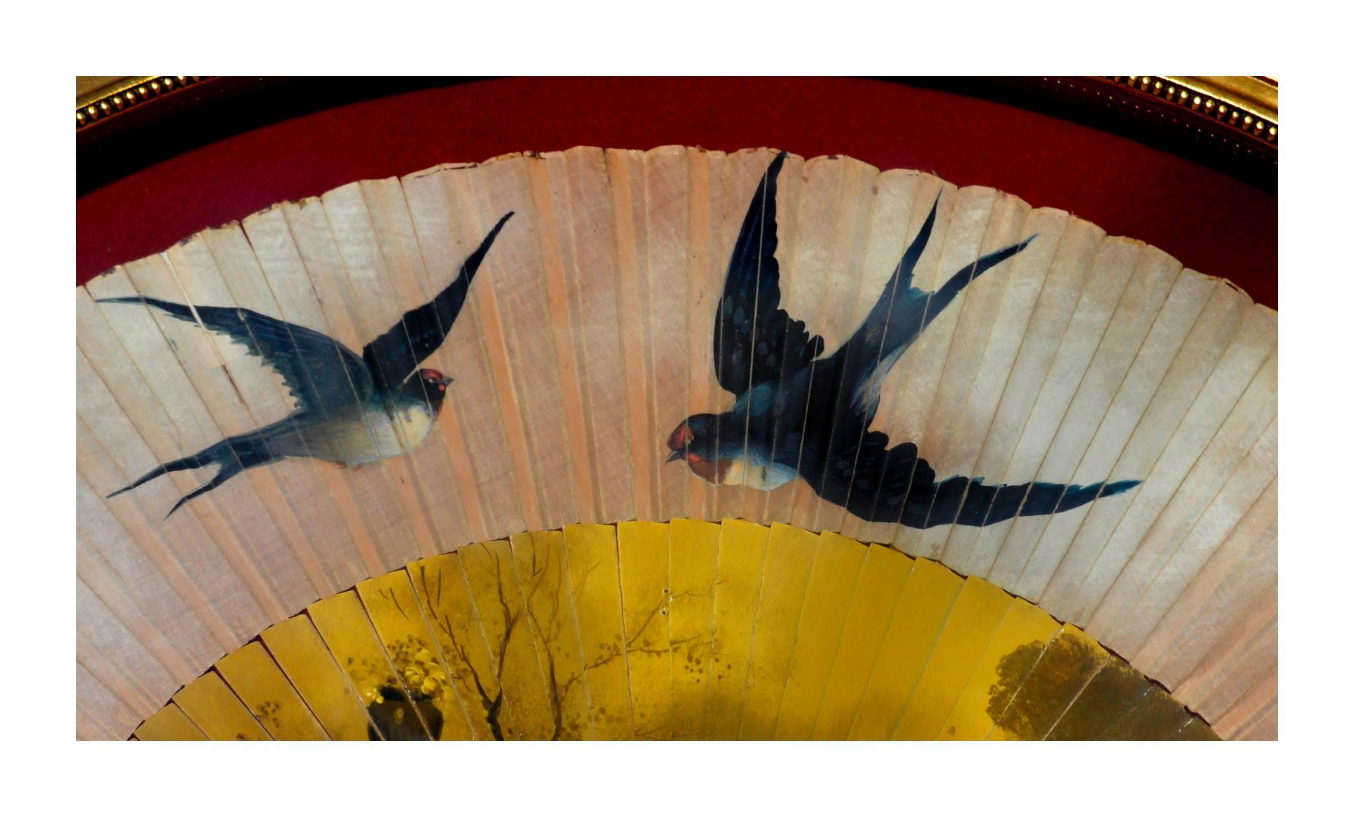Gorgeous antique hand-painted fan. The bottom of the fan shows faint cherry blossom trees next to a marble base and urn, while the upper part of the fan shows four blue sparrows in flight. Painted circa 1900-1910. (Fan appears to be 19th century