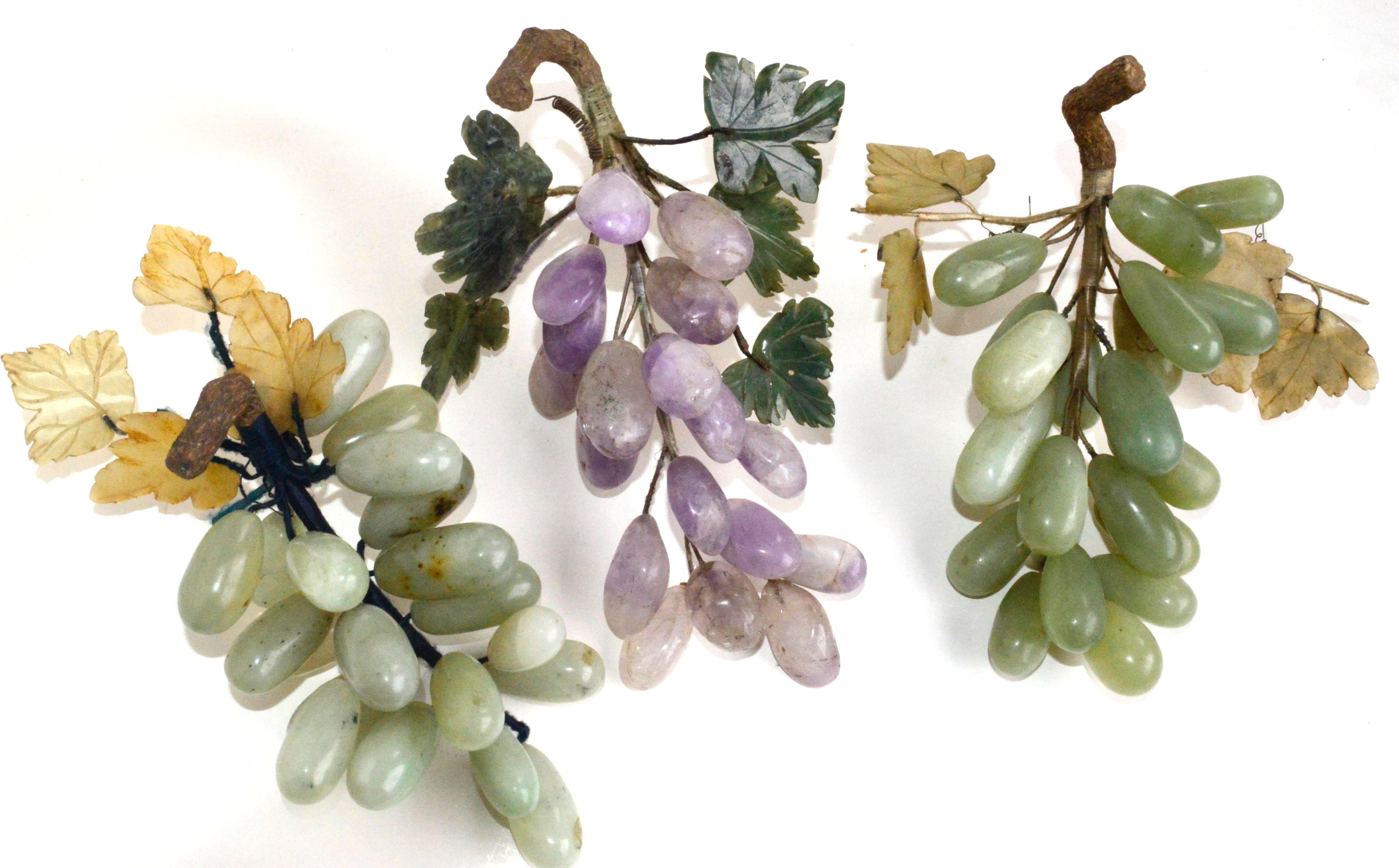 Grouping of three bunches of carved semi-precious stone grapes: One done in Amethyst, two in jade with jade leaves and wood stems. Vintage, handmade in China. Approximate size of each bunch, measures 9