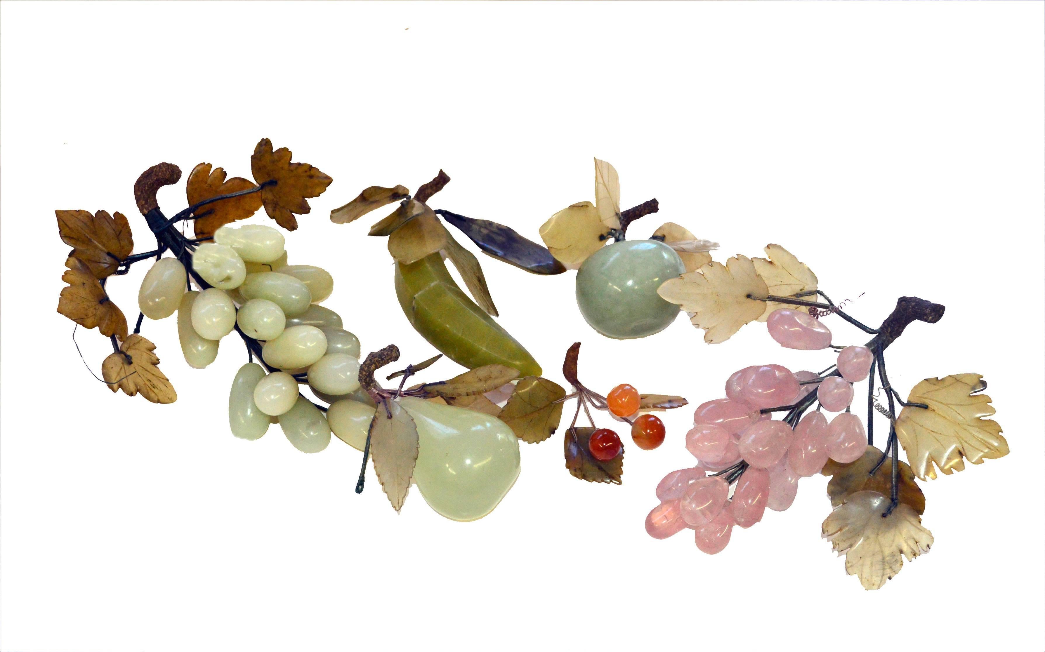 Grouping of two bunches of carved semi-precious stone grapes with jade leaves and wood stems. One bunch of grapes in Jade and one in Rose Quartz and a small bunch of cherries in Carnelian; also assorted fruit carved in semi-precious stone. Grouping