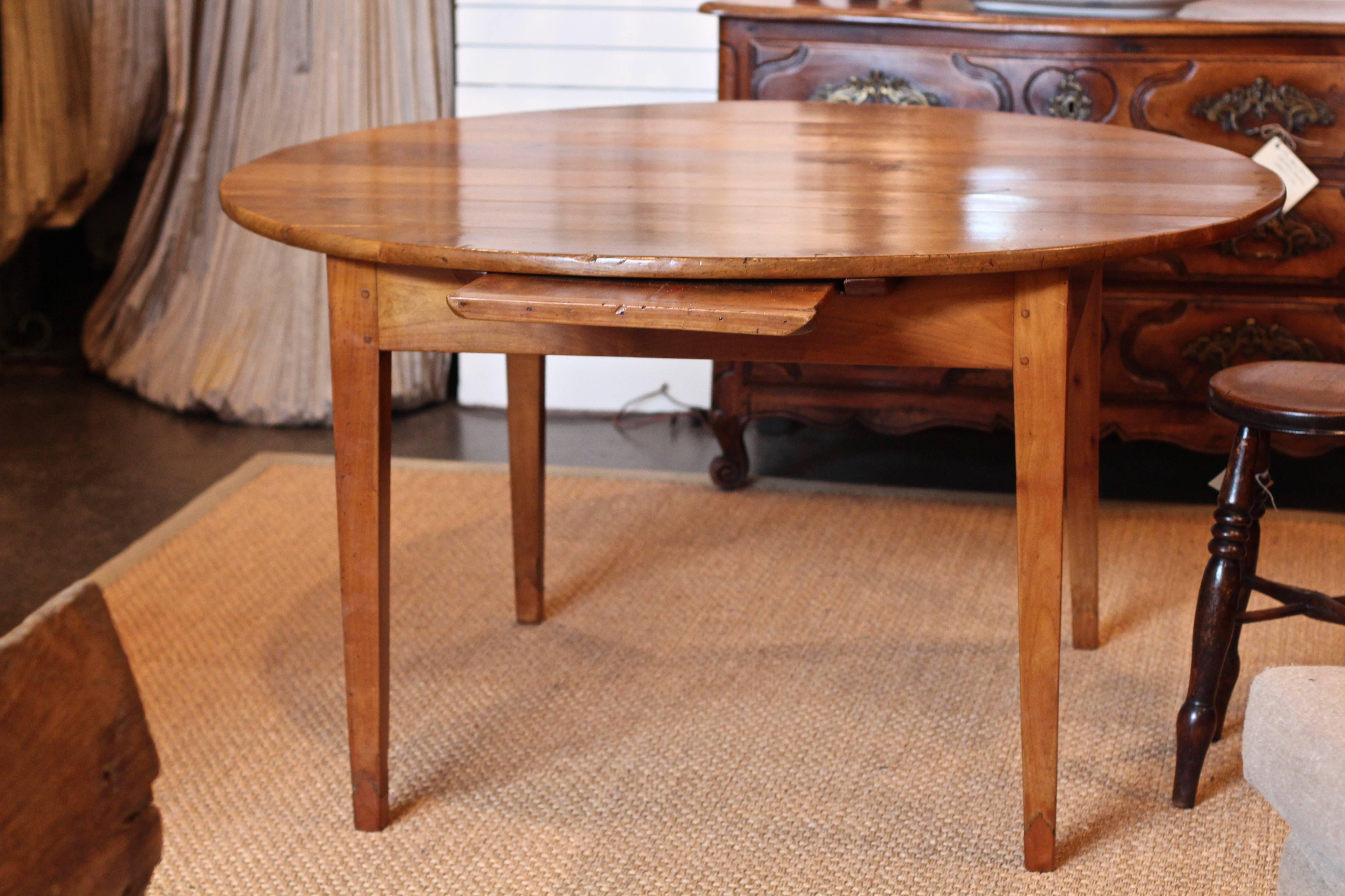 French 19th century cherrywood circular dining table with square tapered legs. Fitted bread slide to the frieze.