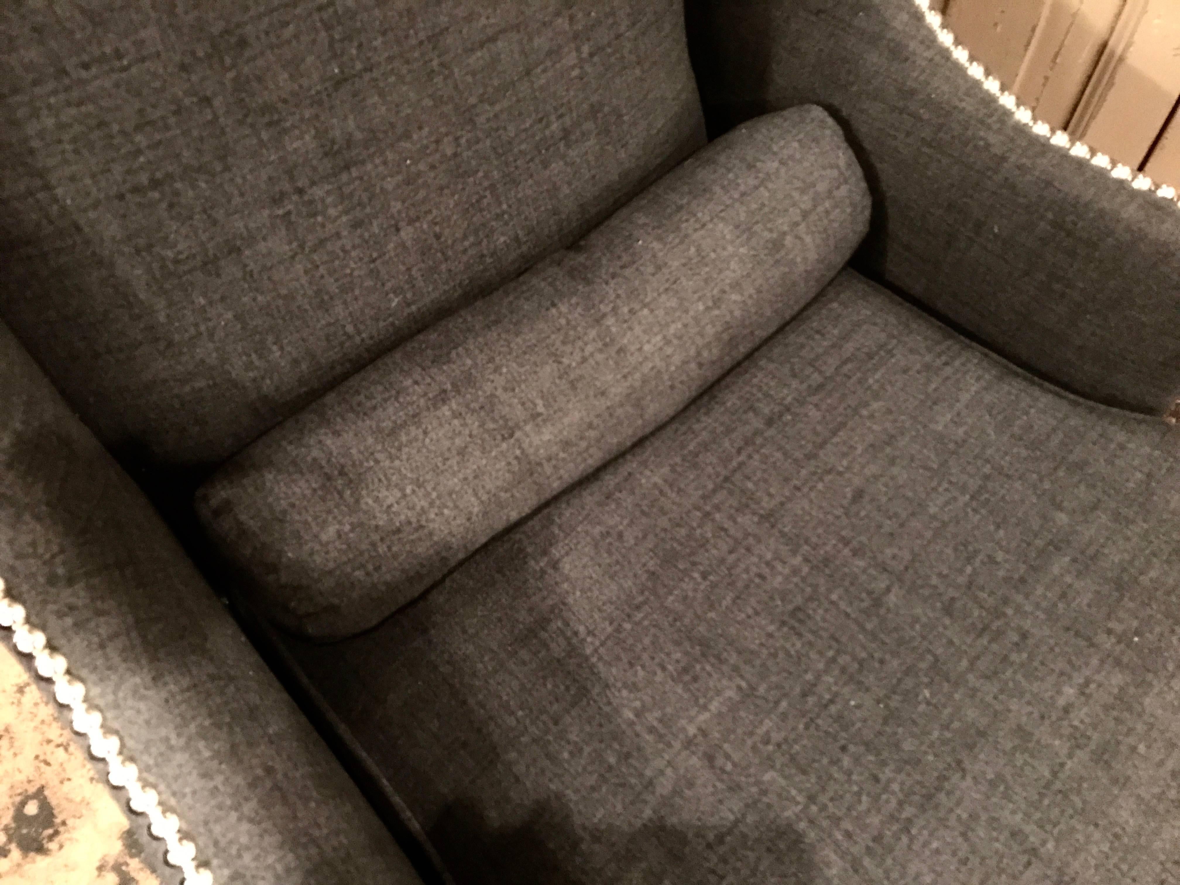 Early 20th century French wing chair. Freshly upholstered in dark grey flannel with silver nailheads. Handsome and very comfortable.