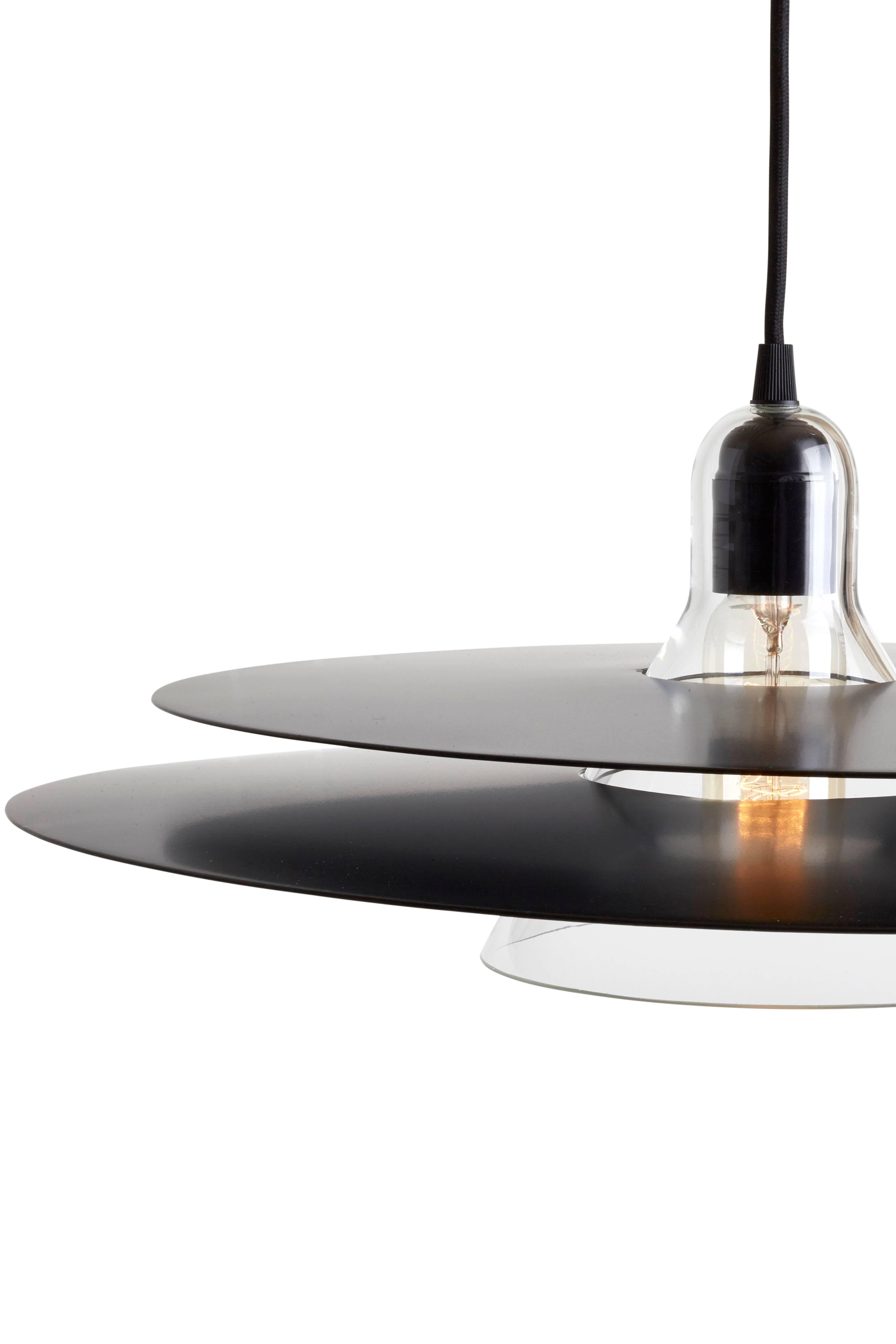 Cymbal is a pendant lamp made of blown glass and two slightly convex trays. The chrome version looks transparent as it rejects its environment, whereas the black one overs a more graphic style. Cymbal can be displayed both alone or in combination