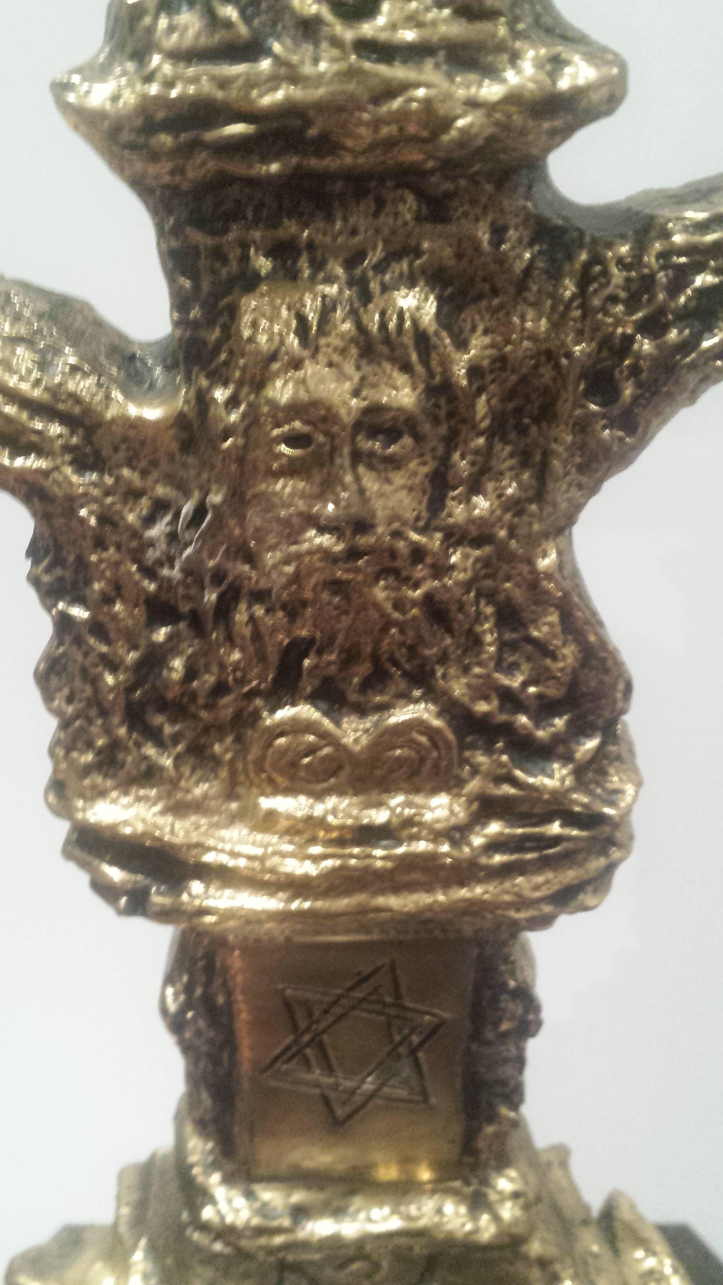 A Beautiful Judaica Gilt Bronze Sculpture of a Menorah, Salvador Dali, of seven-branched tree form, both sides centered by a head of Moses above a Star of David, the sconces with Hebrew inscriptions, mounted on a rough dark blue stone.
Signed and