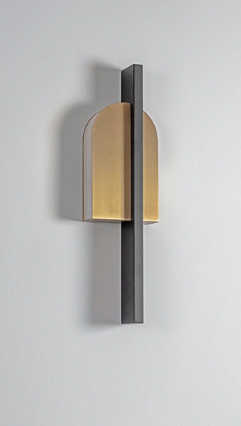 Brass Single Wall Light by Square in Circle
Dimensions: W 14 x H 50 x D 7 cm
Materials: Brushed brass finish, black powder-coated metal

Inspired by geometric forms, an extruded semicircle is cut in half and then cut again. A rectangular panel was