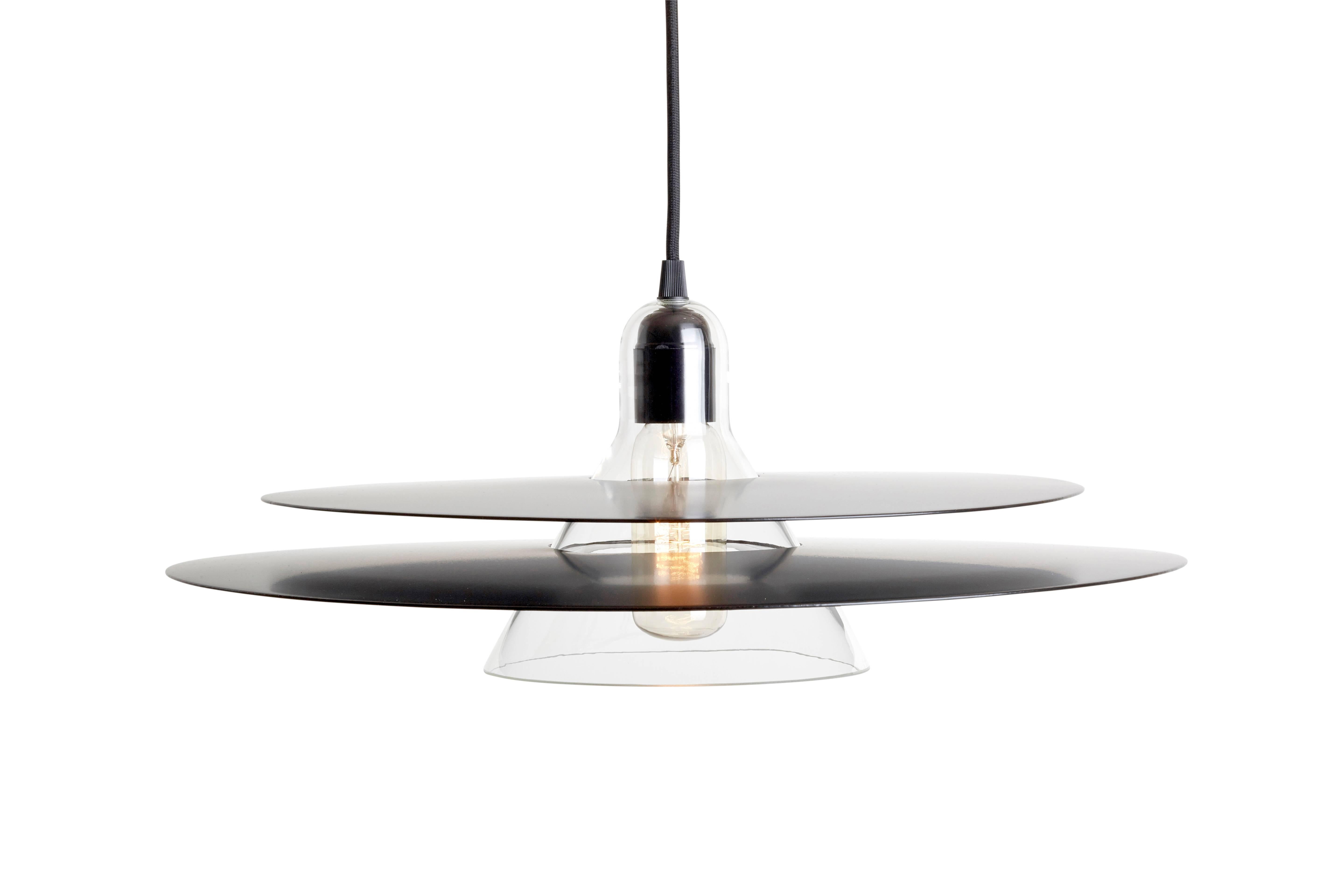 Cymbal is a pendant lamp made of blown glass and two slightly convexe trays. The chrome version looks transparent as it reflects its environment, whereas the black one orders a more graphic style. Cymbal can be displayed both alone or in combination