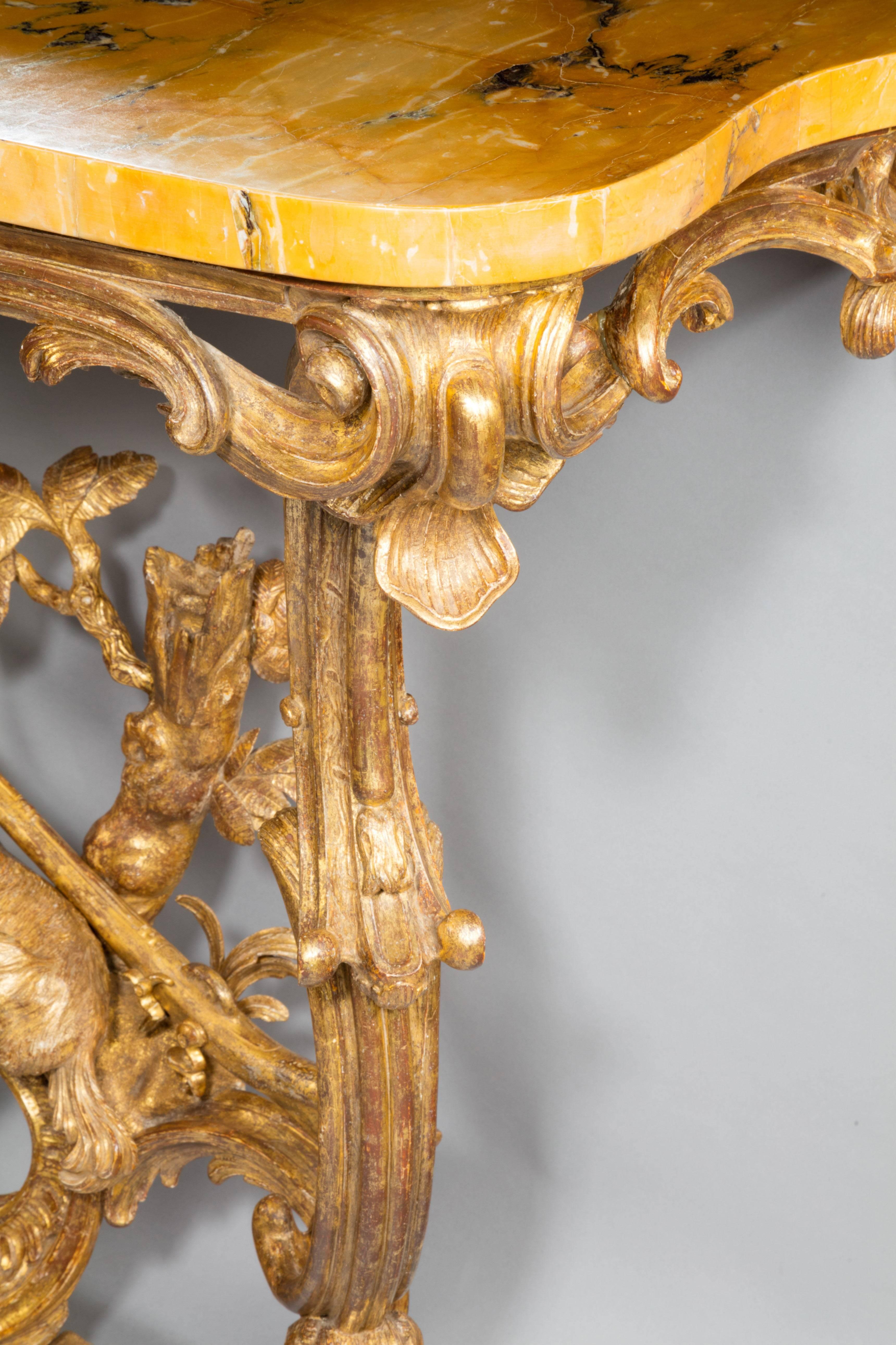 With a shaped, serpentine fronted Brocatello Di Siena marble top above a giltwood apron/frieze, pierced with foliate scrolls, rocailled and with bold cabochons at the front corners. 

Both of the legs comprise of two carved ‘C’-scrolls, joined at