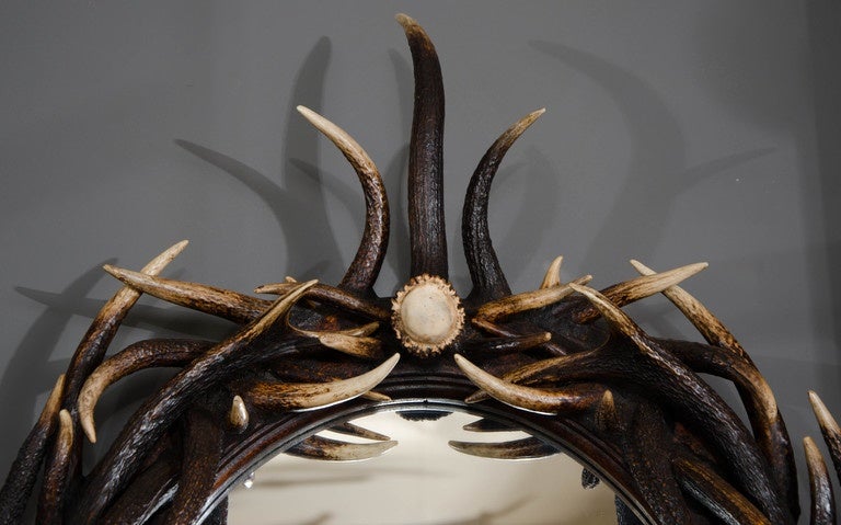 This marvelous and unique oval wall mirror is comprised of naturally shed large red deer from Scotland surrounding an oval mirrored glass center. The individual natural beauty of the dark antler horn combined with the functionality and artistic