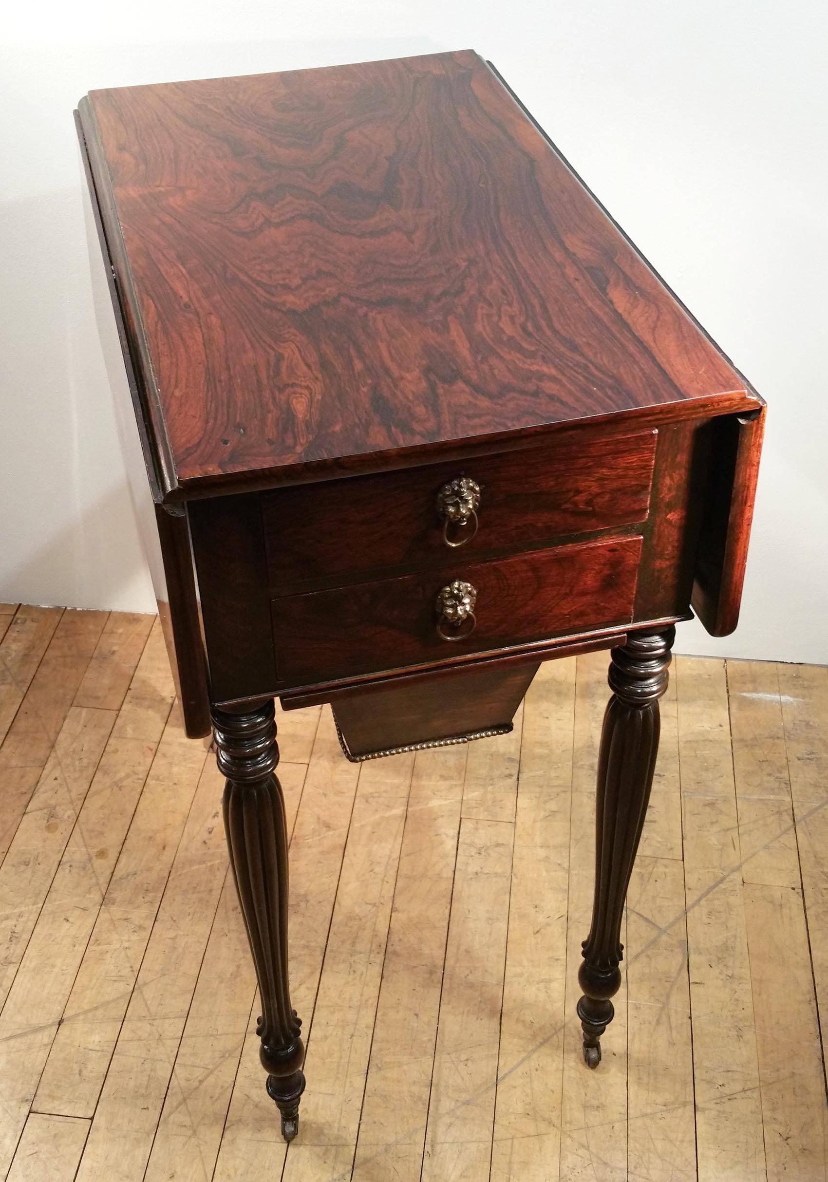 This very attractive and beautifully paginated Mid 19th C. Rosewood Pembroke Work Table stands on slender reeded legs with leather and brass castors. 
The front of table has 2 top drawers decorated with brass lion ring pulls and a work drawer that