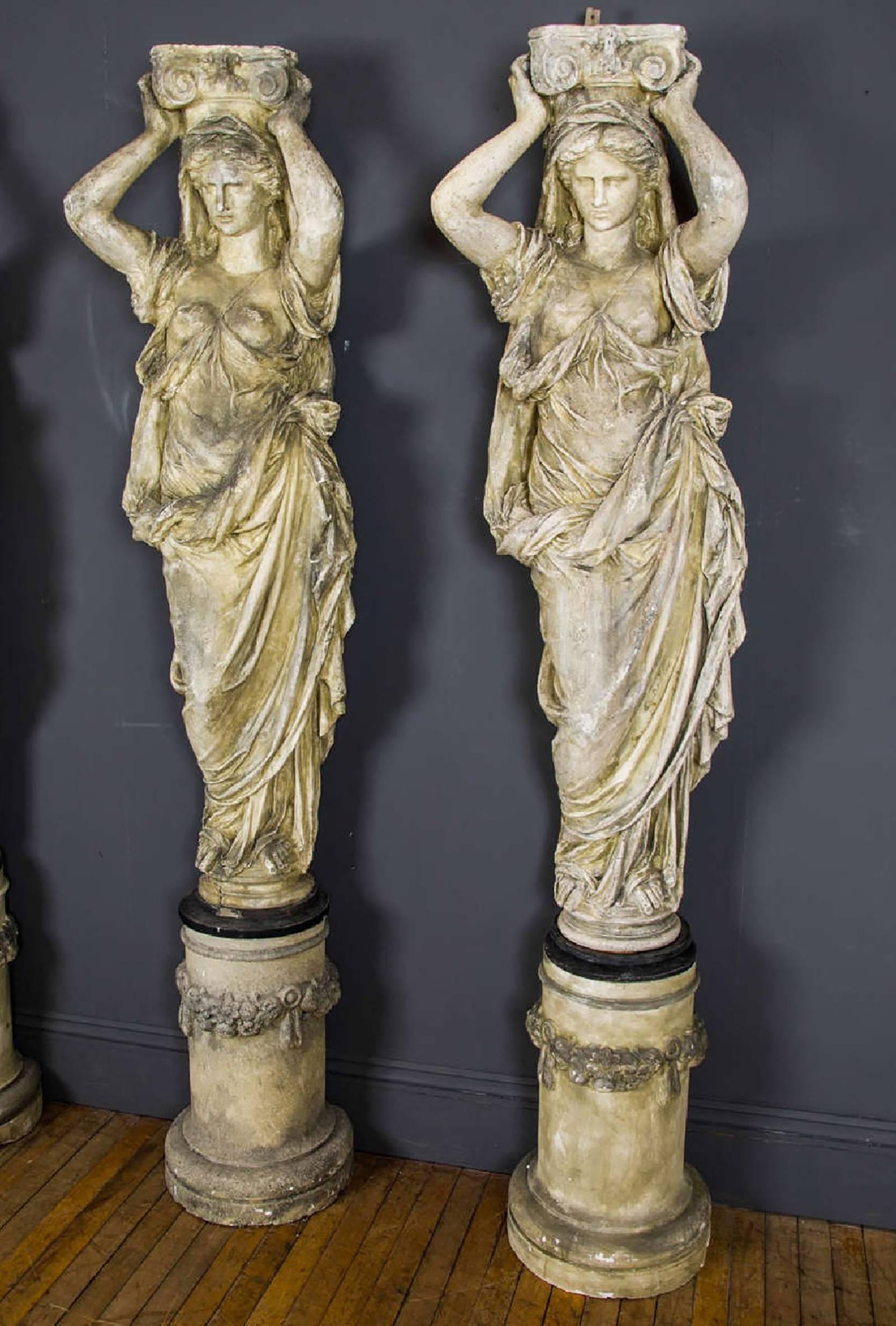 A beautiful and elaborate pair of French caryatids, of plaster construction, depicting ancient classical Greek female figures supporting Corinthian capitals standing on decorated bases. Each figure measures 80 in – 203.2 cm in height, 19 in – 48.2