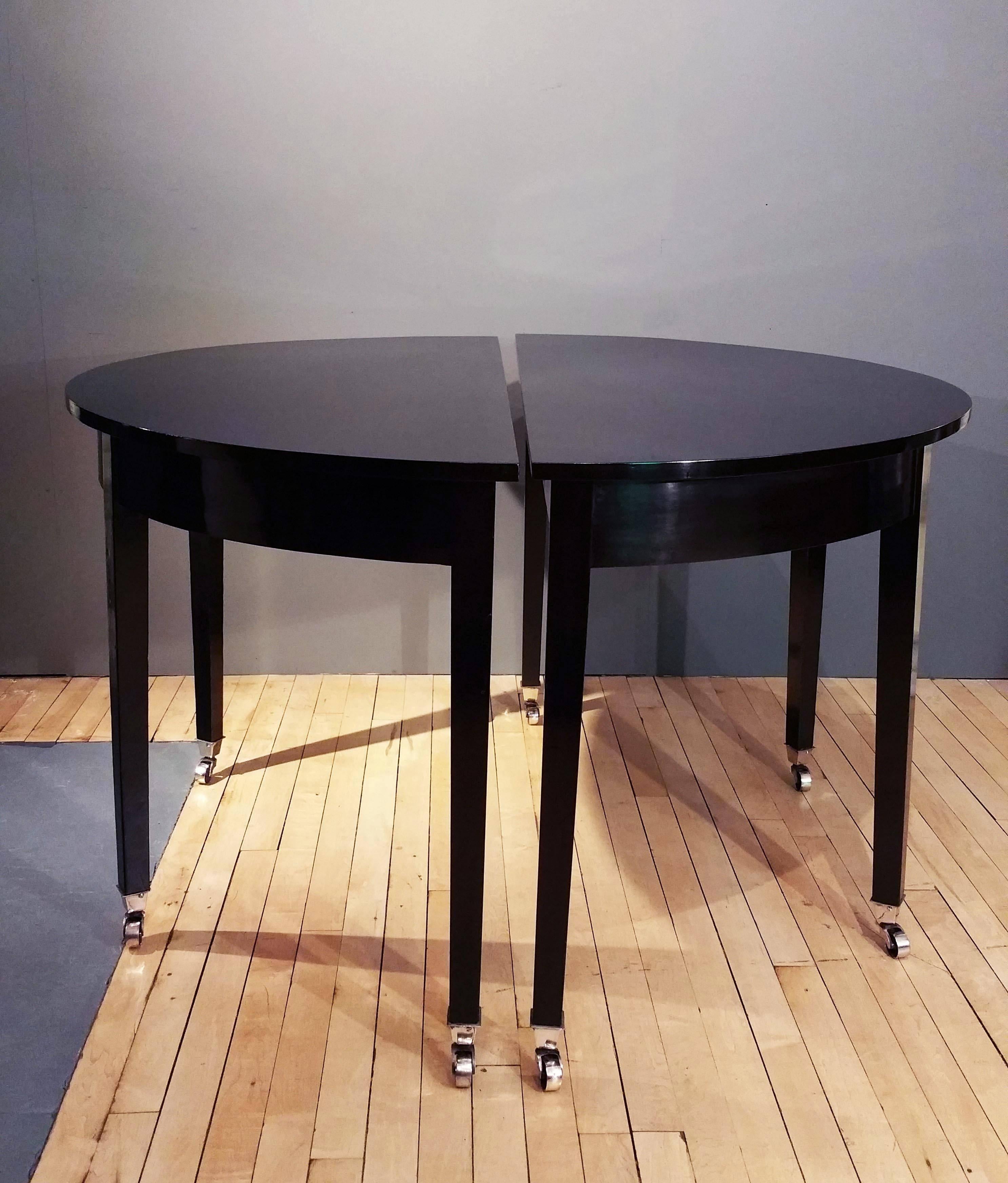 This beautiful pair of early 19th century demilune console tables features a well-proportioned size to work in a variety of home settings. The mahogany tables have been refinished in a sleek and high gloss black lacquer finish and are supported on