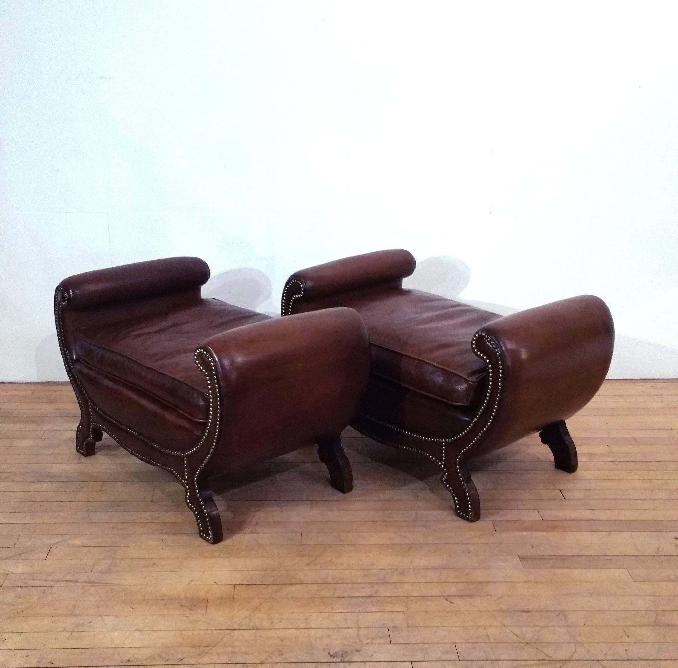 This very attractive and versatile pair of window seats has been upholstered in rich warm Cognac brown leather with metal stud detailing. They were designed in the Regency style and feature curled arm supports and a separate seat cushion. Each seat