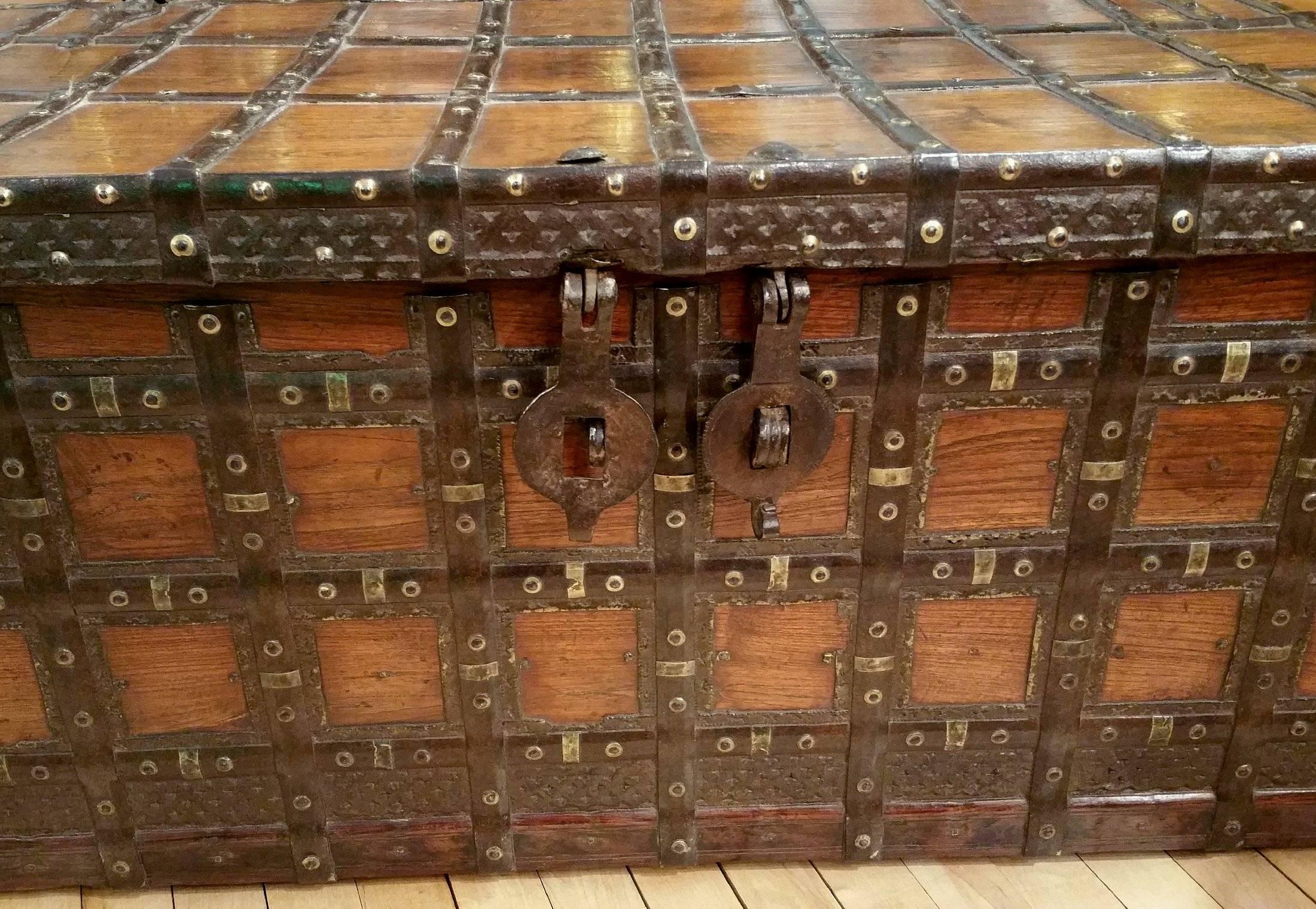 This very handsome and well-proportioned 19th century, Anglo-Indian teak chest features a series of iron bands and straps which wrap around the entire piece. The front has a double catch lock and a candle box on the inside. It measures 51 ½ in – 130