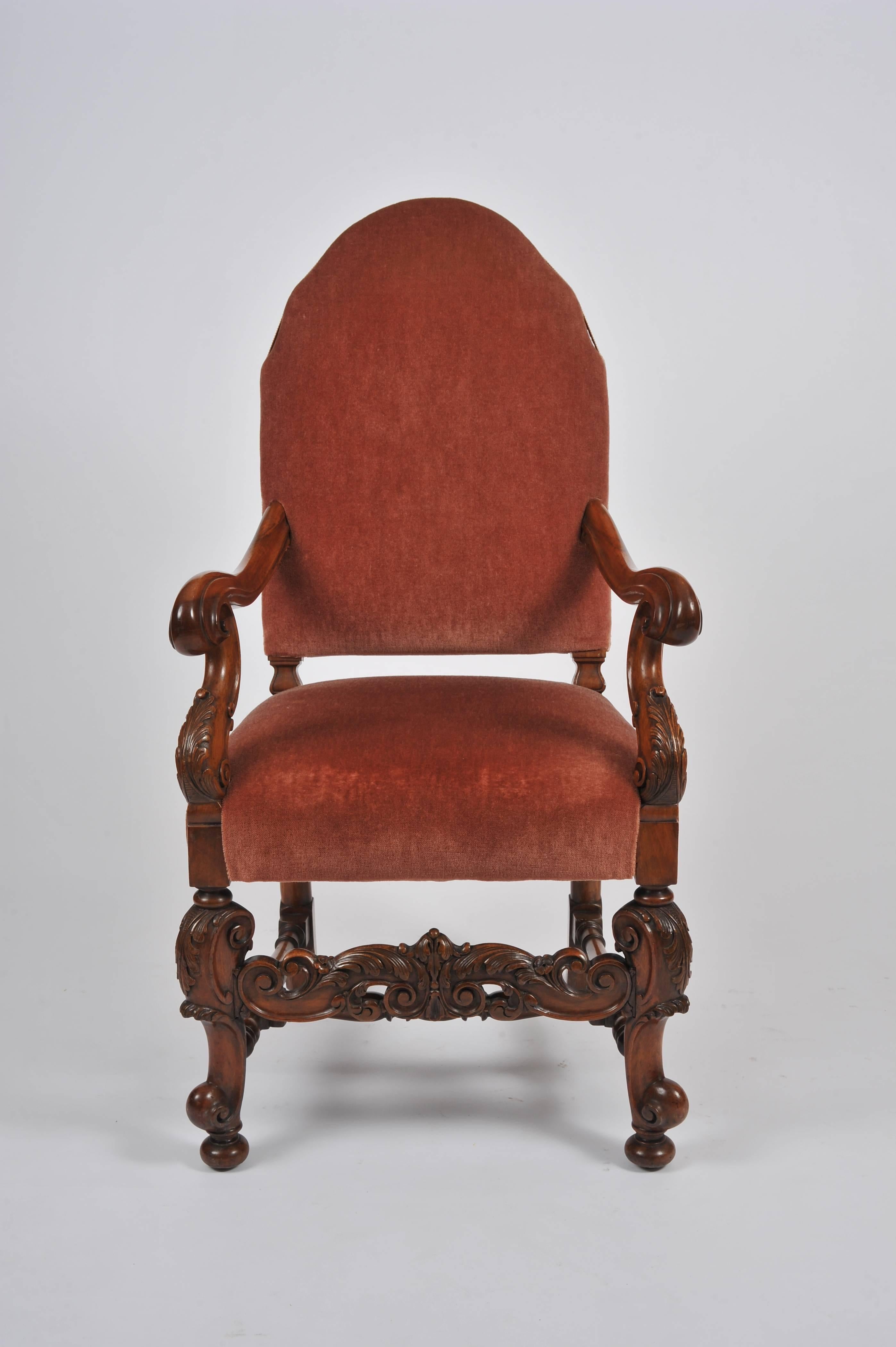 This striking and very comfortable set of ten English walnut dining chairs are comprised of 8 side chairs and 2 carvers in the Carolean style. Each chair features ornate carving details of acanthus leaves and scroll work with a stretcher bar base.