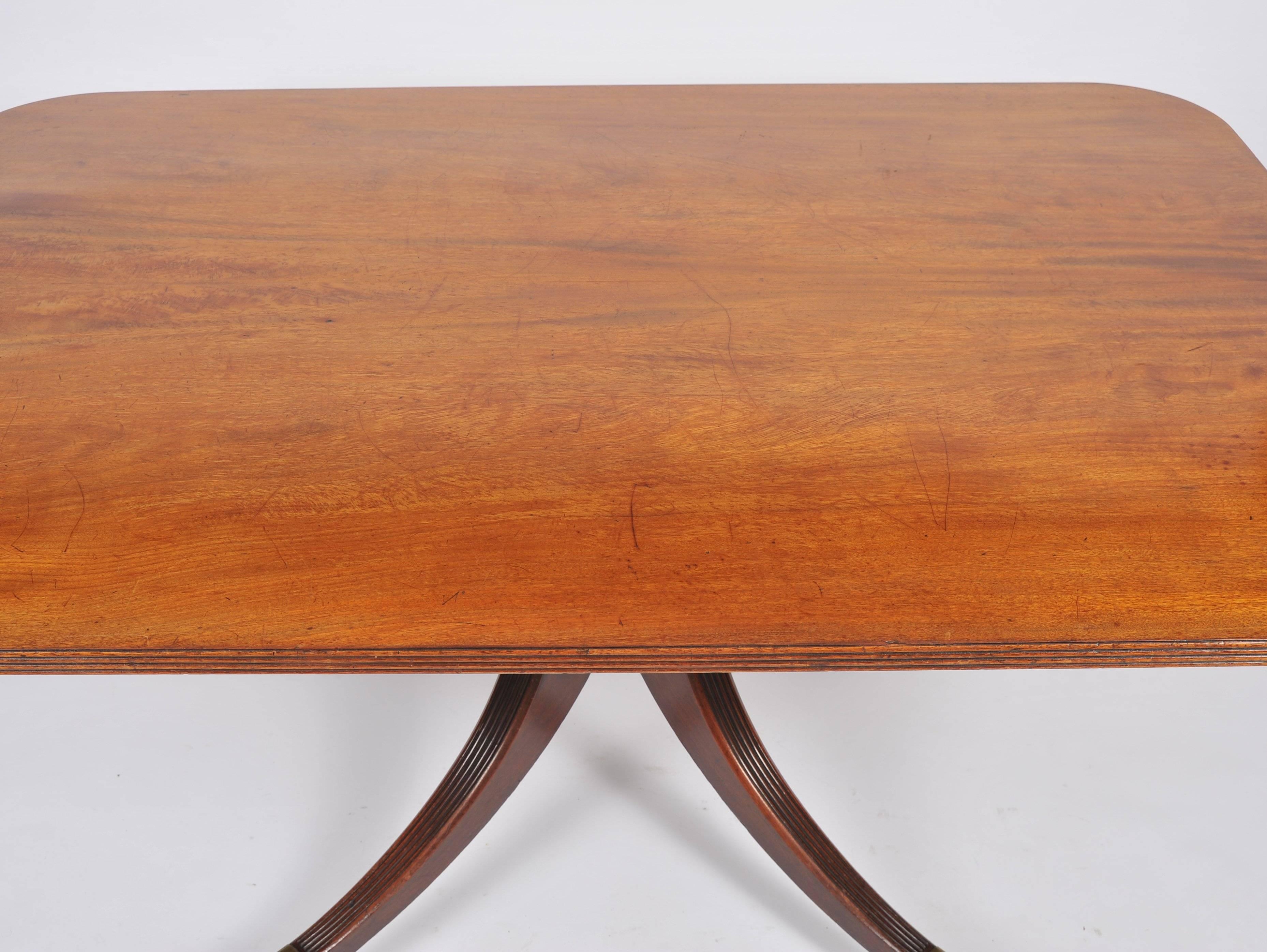 This wonderful and very versatile sized rectangular mahogany breakfast table features a substantial top with a reeded edging. The table has a space saving tilt top feature and is supported on a central column with a Quadra form base on swept back