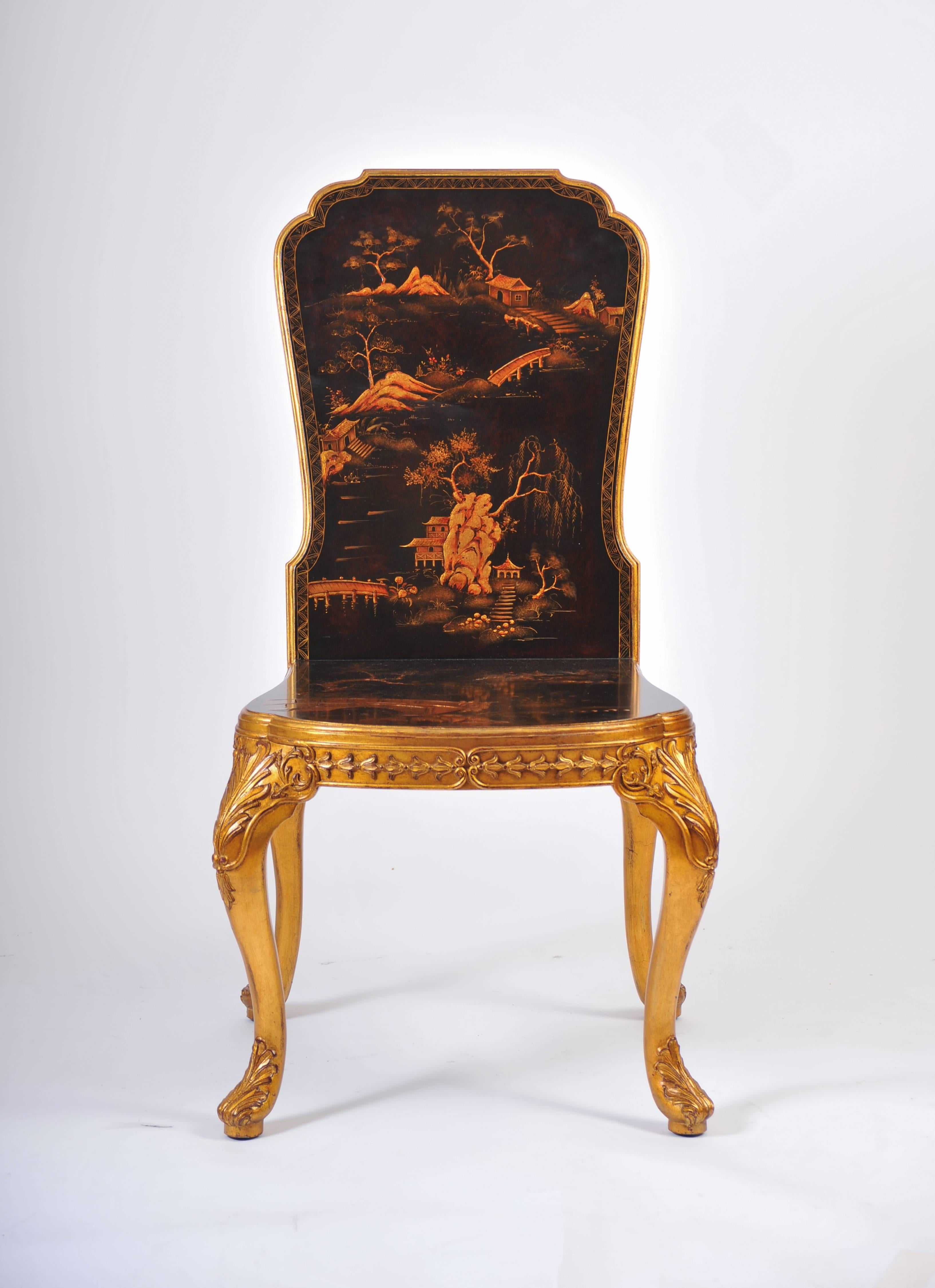This beautiful and very ornate pair of 18th century style chinoiserie hall chairs feature gilded cabriole legs with acanthus leaf detailing. The chairs depict various outdoor oriental scenes on both the front and back of the chair as well as the