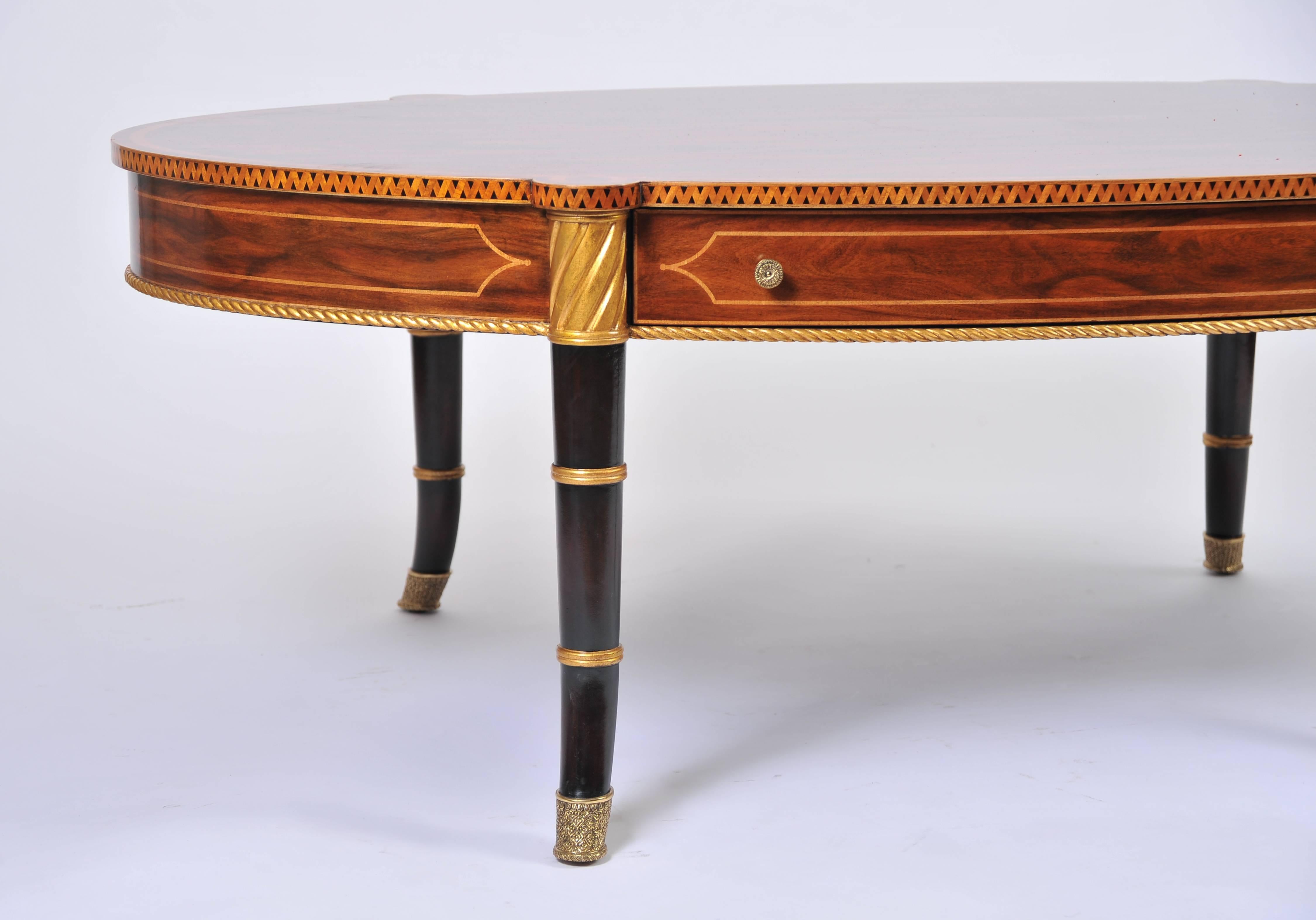 This beautiful and highly decorative oval rosewood coffee table features a satinwood crossbanding with ebonized and gilded legs. It measures 57 ¾ in – 146.7 cm wide, 35 in – 89 cm deep and 19 ¾ in – 50.2 cm high. This fine quality coffee table would