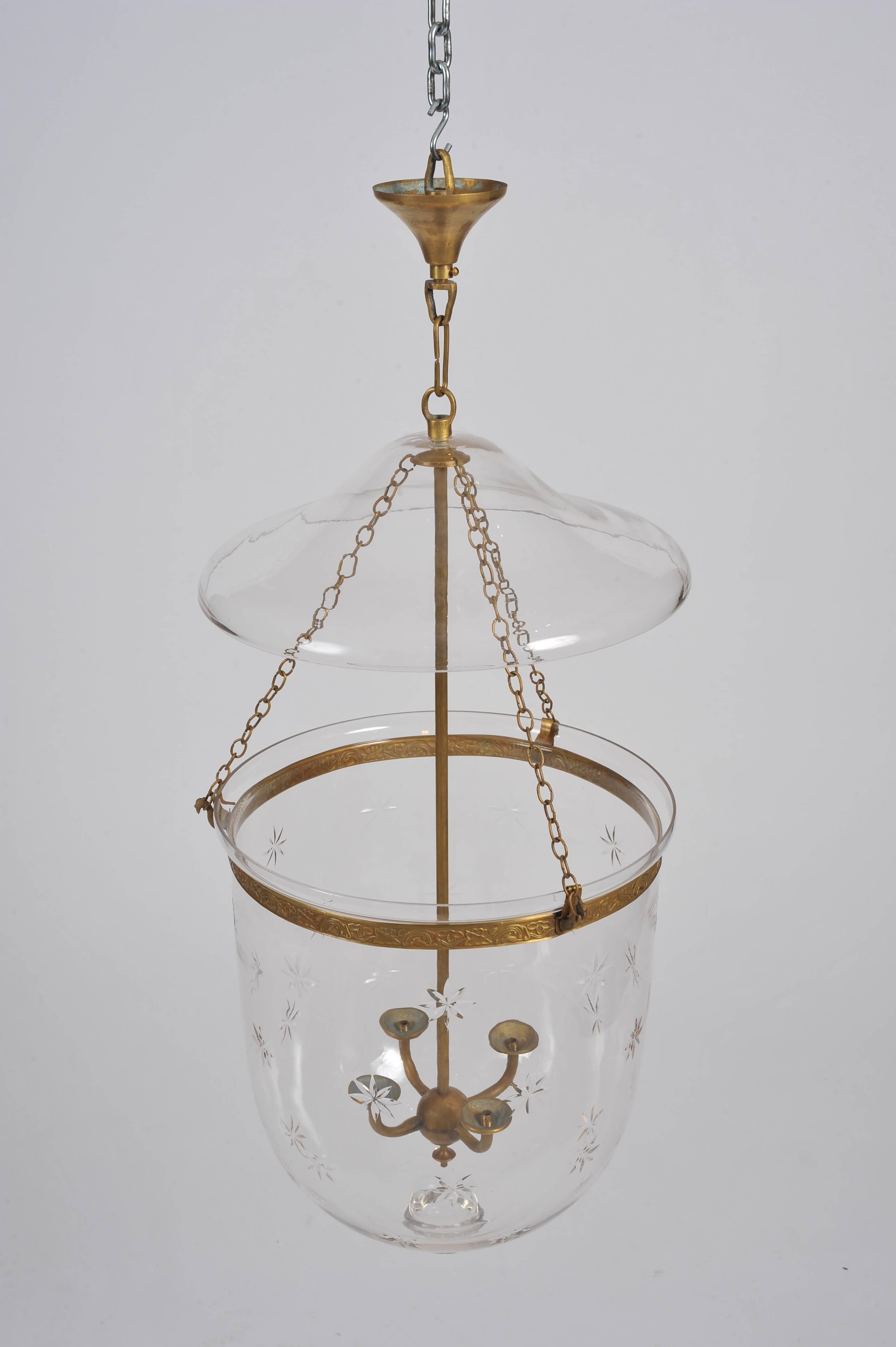 This elegant and well-proportioned handmade glass storm lantern features a blown clear glass shade with a cut glass star design and polished brass hardware. The lantern has a separate top plate and features an internal 4 light fitting. The light