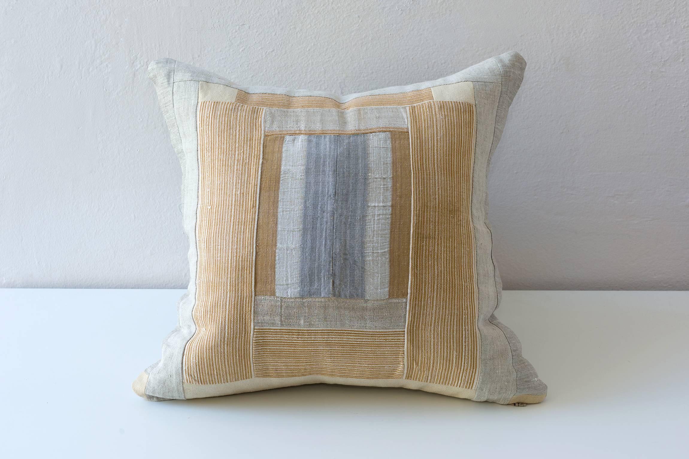 Oso Oke piecework cushion. Narrow loomed textile by the Yoruba, Nigeria. Gold and butterscotch stripe and the other in a silver and tan stripe with a Lurex metallic silver composed with a coordinating linen. 

Linen on reverse as the border on the