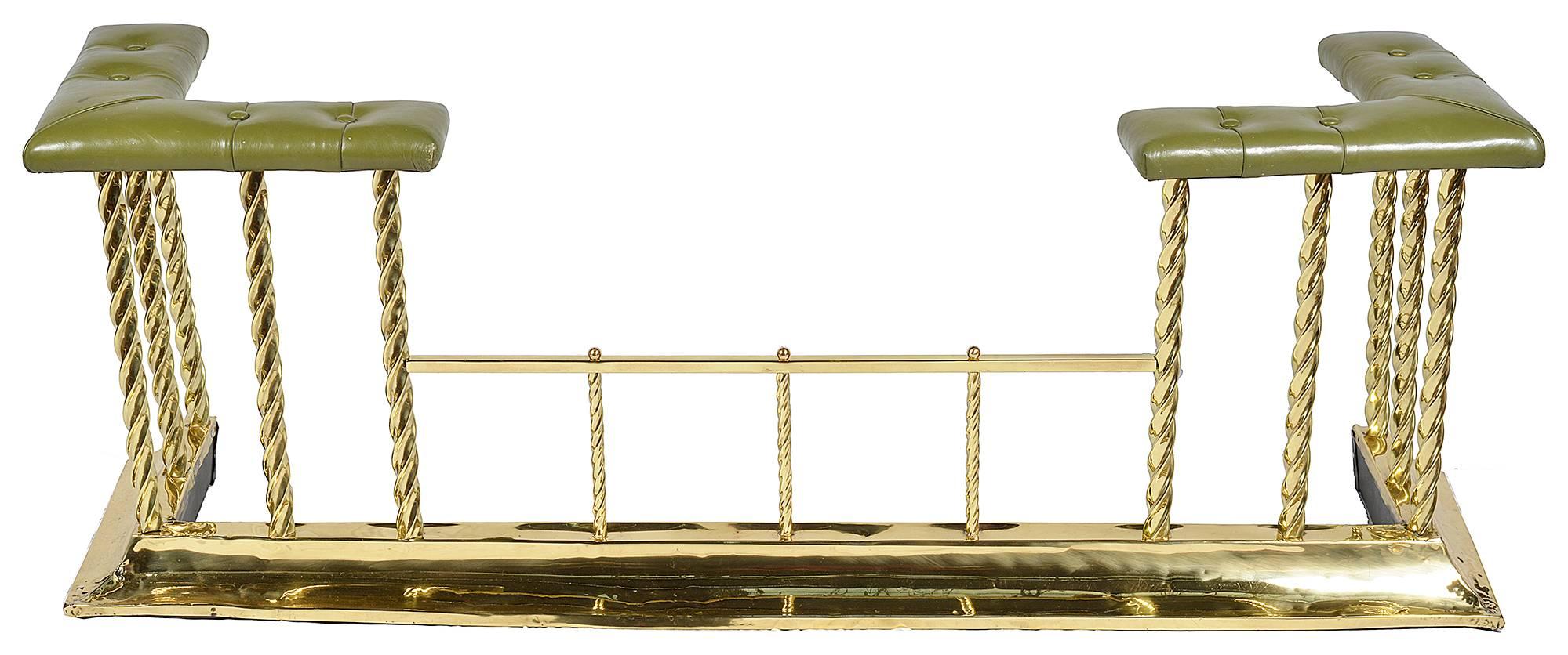 A good quality 19th century brass club fender, having buttoned hide upholstery, barley twist brass rods and an out swept brass base.