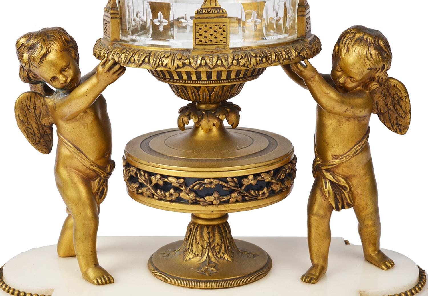 A very good quality late 19th century Louis XVI style ormolu and cut-glass revolving mantel clock. Having cherubs on either side support the glass case with classical gilded ormolu swags and foliate decoration. Revolving enamel numerals to the clock